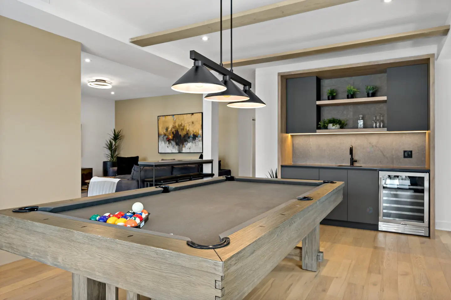A game room with a pool table, a wet bar with a wine fridge, and a black pendant light.