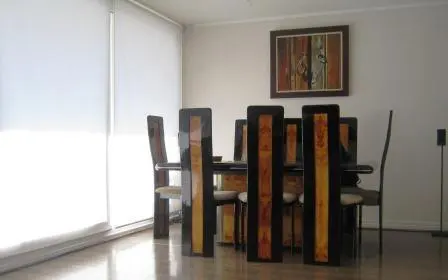 Dining room with a dark wood table and chairs, light wood floors, and white walls. A colorful painting hangs on the wall.