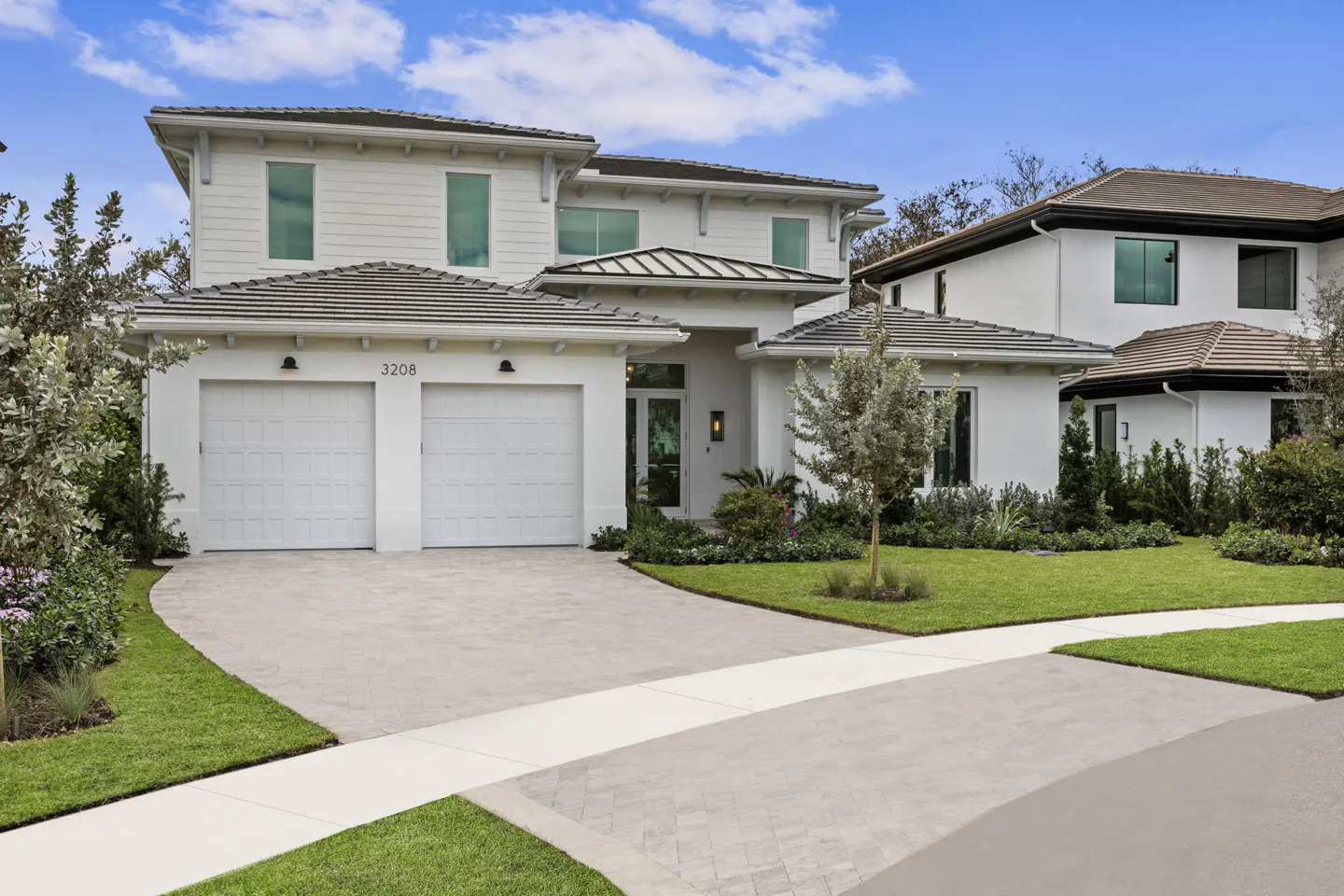 Two-story white house with a gray roof, two-car garage, and a driveway leading to the street.