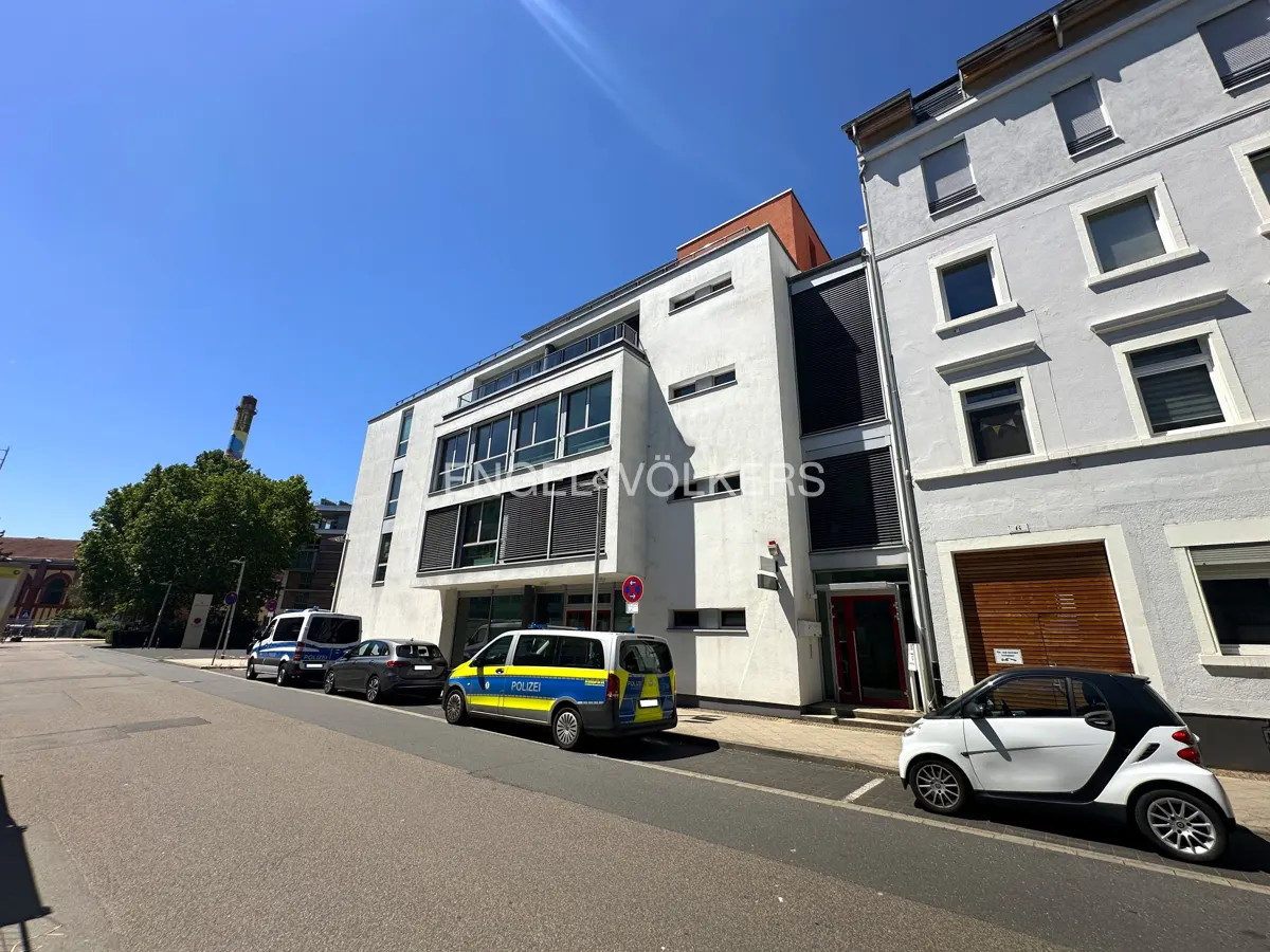 Exterior view of a modern white building with police cars parked in front on a sunny day.