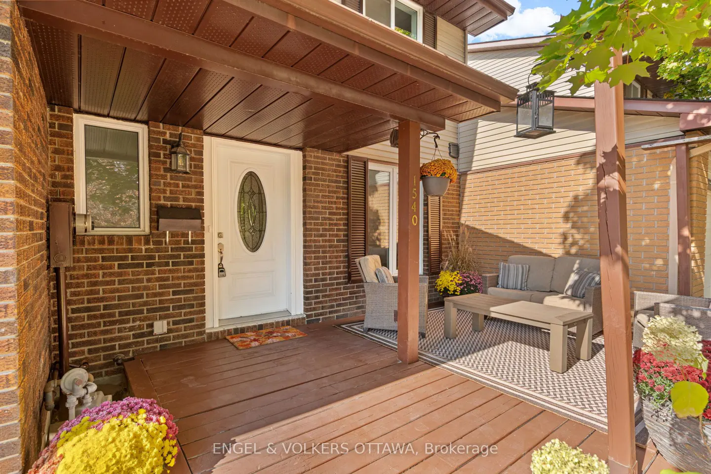 Covered porch with a white front door, brick walls, and outdoor furniture including a sofa and coffee table.