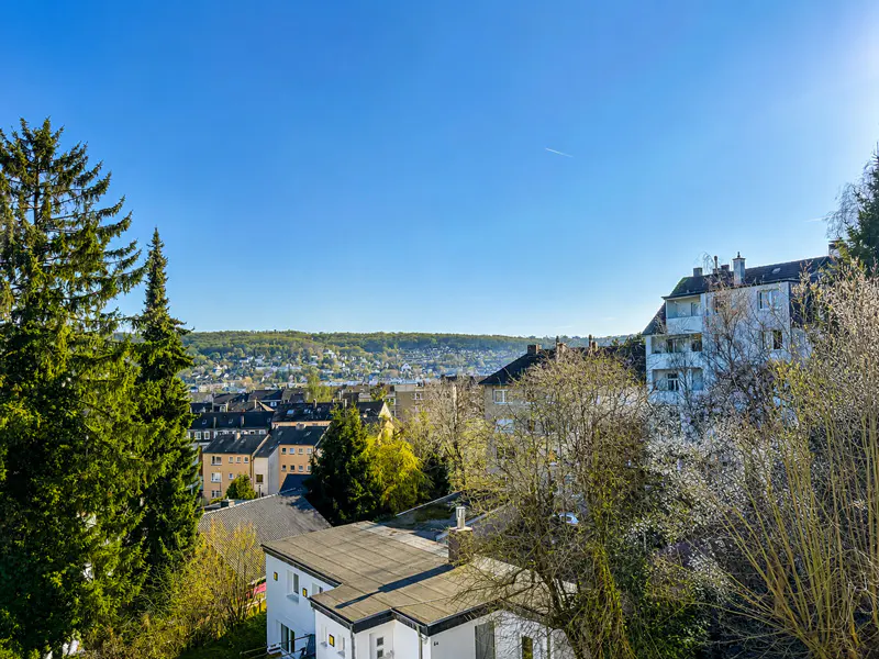 View of a European town with houses, trees, and a clear blue sky.