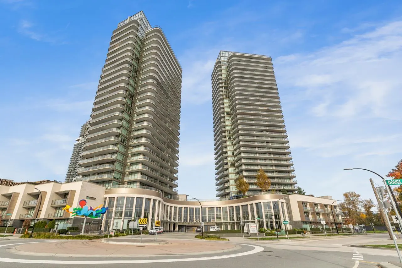 Two modern, high-rise condo towers with curved balconies, connected by a lower building with a curved facade, under a blue sky.