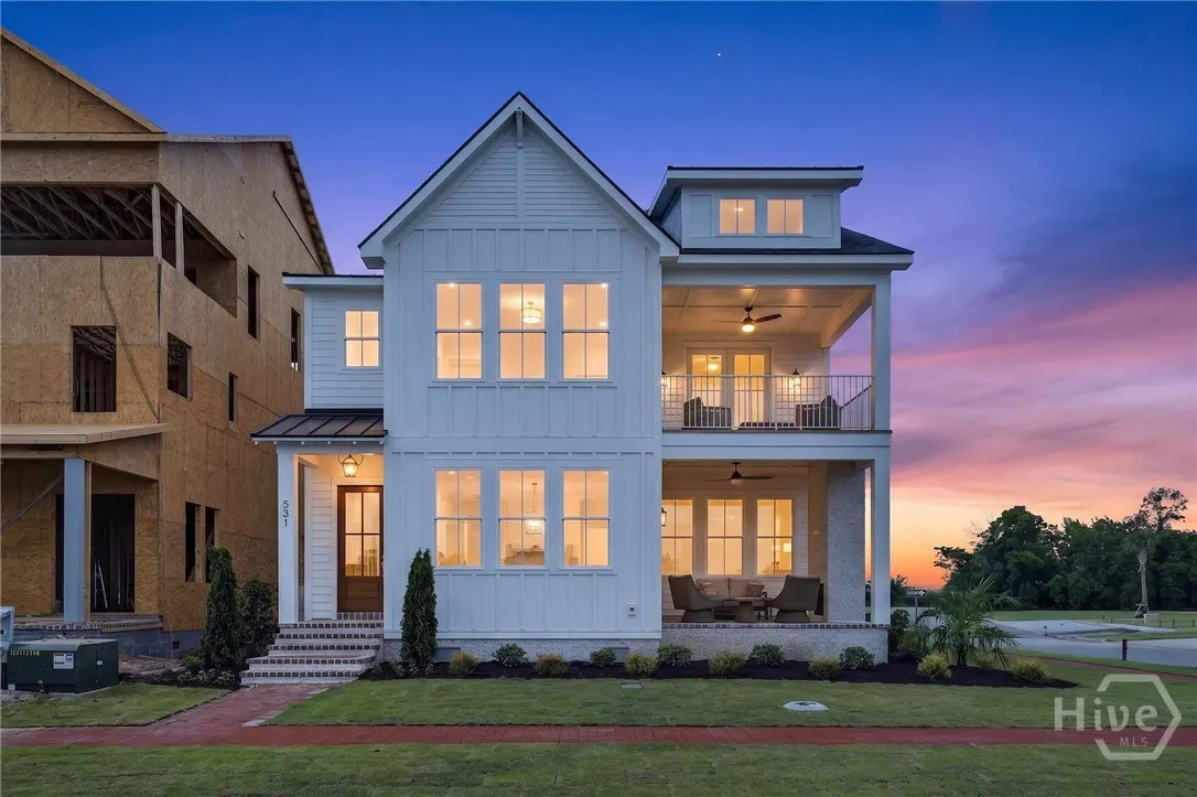 Two-story white house with a brown door and two balconies at dusk.