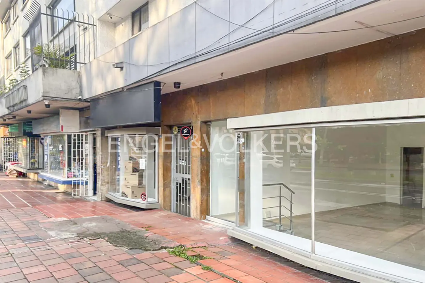 Exterior view of Engel & Volkers real estate storefront with glass windows and doors on a red brick sidewalk.