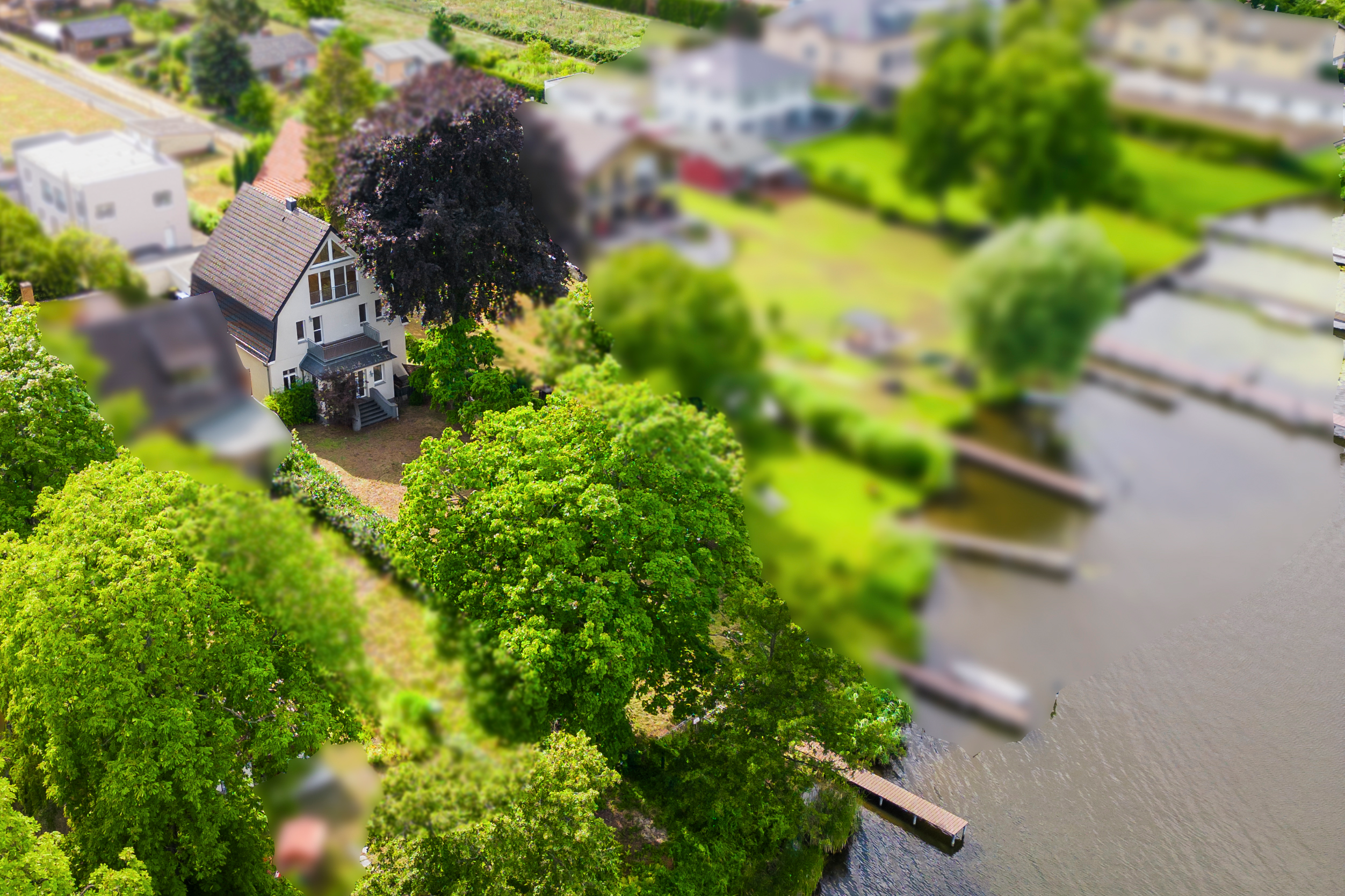 Aerial view of a white house with a dark roof nestled among lush green trees next to a river with small wooden docks. [AI-generated text]