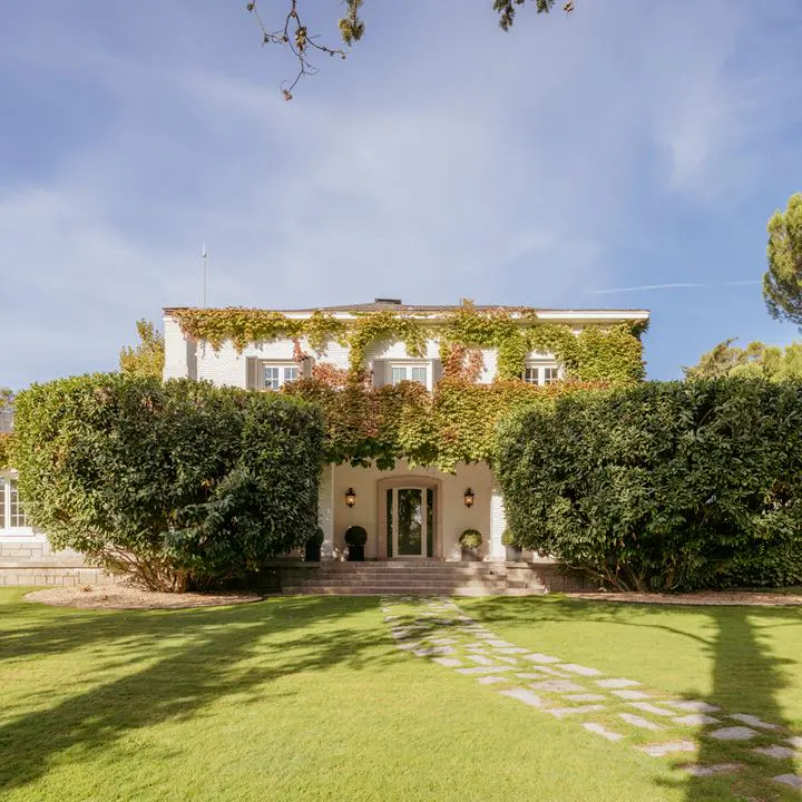 Exterior of a white two-story house with green ivy, dark trim, and a stone path leading to the front door.