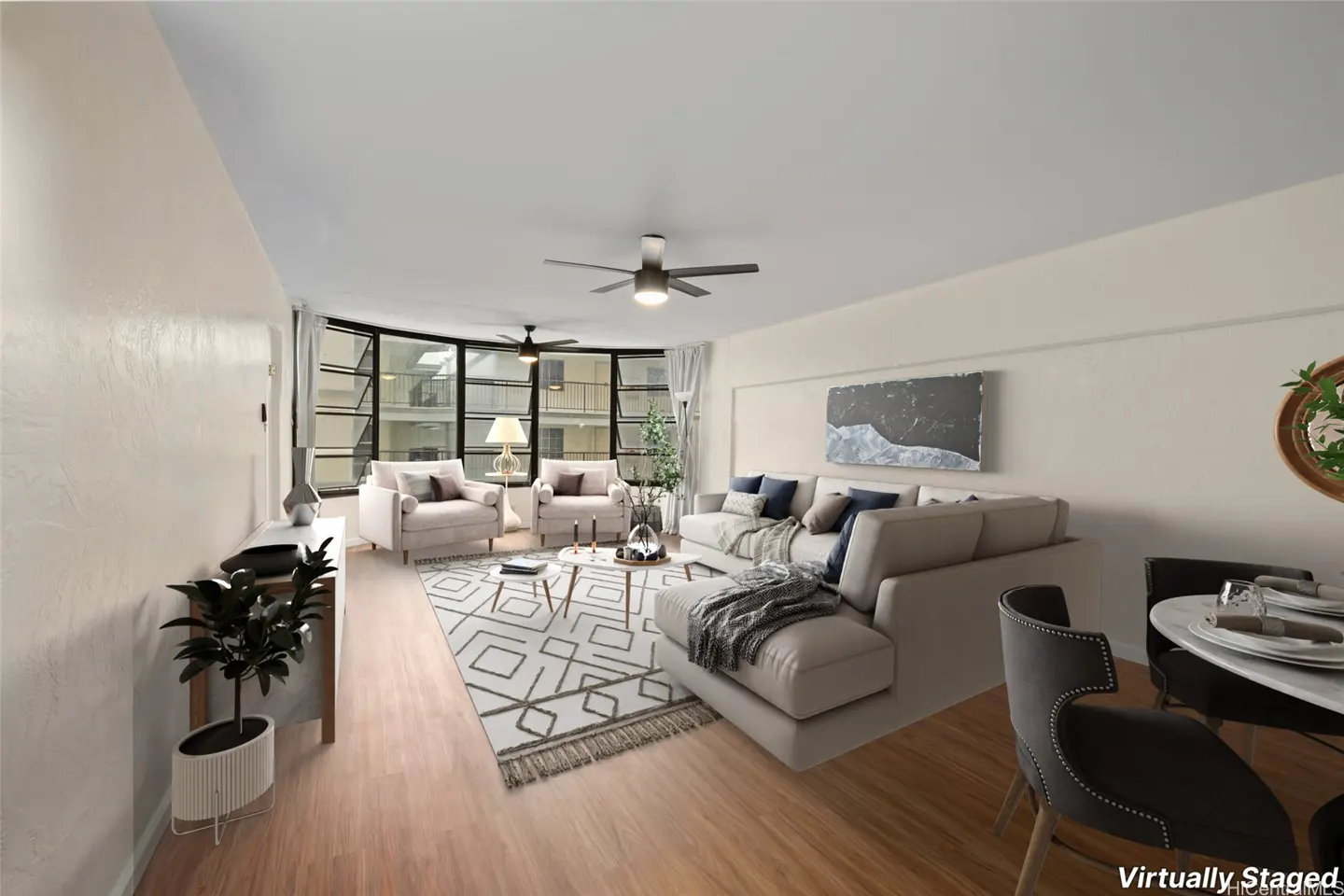 Living room with beige walls, wood floors, and a geometric rug. A sectional sofa and two armchairs face a large window.
