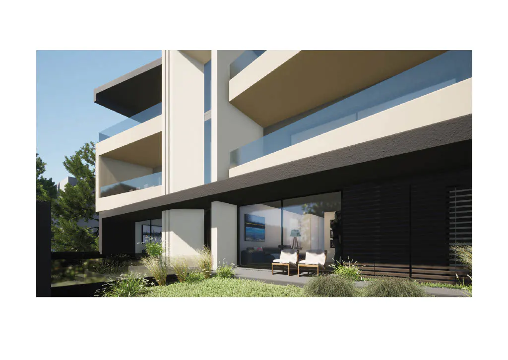 Modern apartment building with glass balconies and a patio with two chairs.