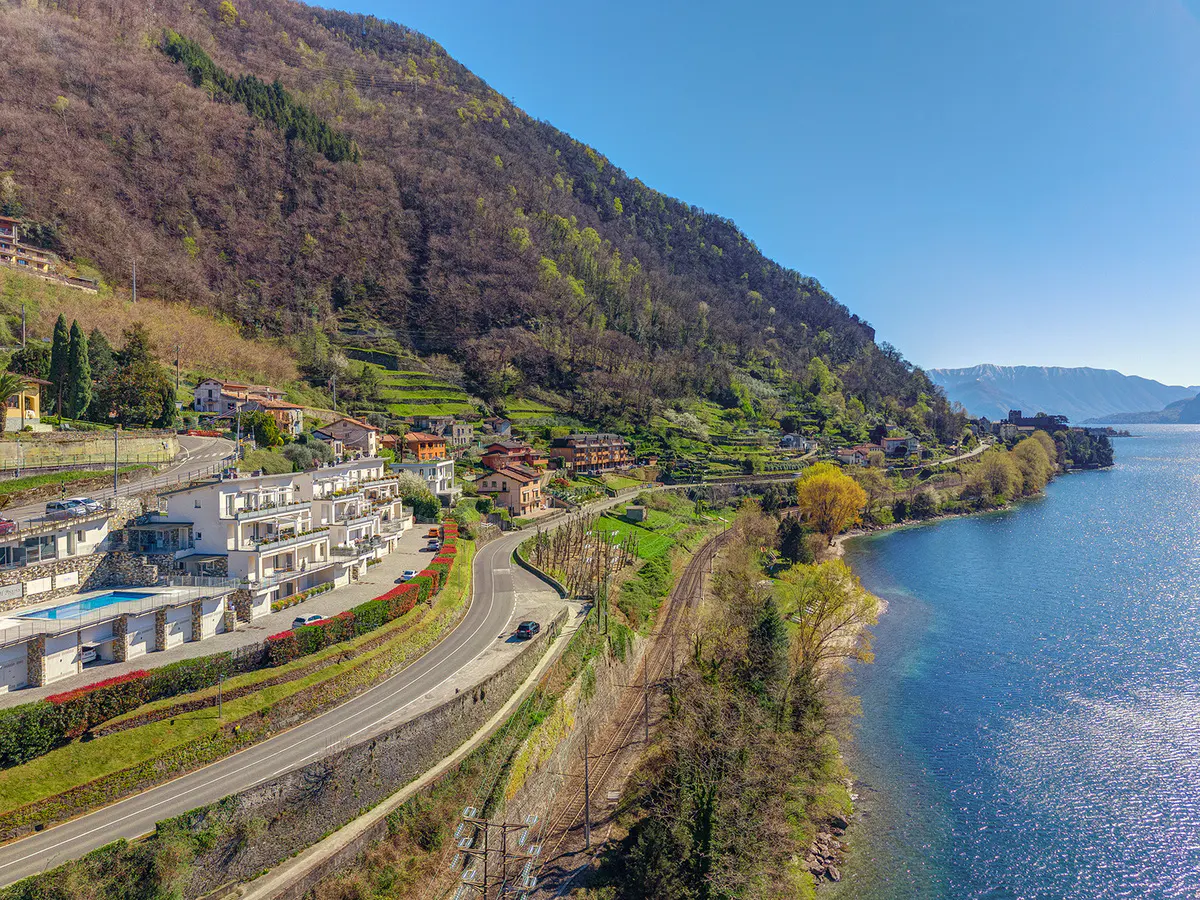 Scenic view of Lake Iseo, Italy, with mountainside homes, a winding road, and blue water under a clear sky.