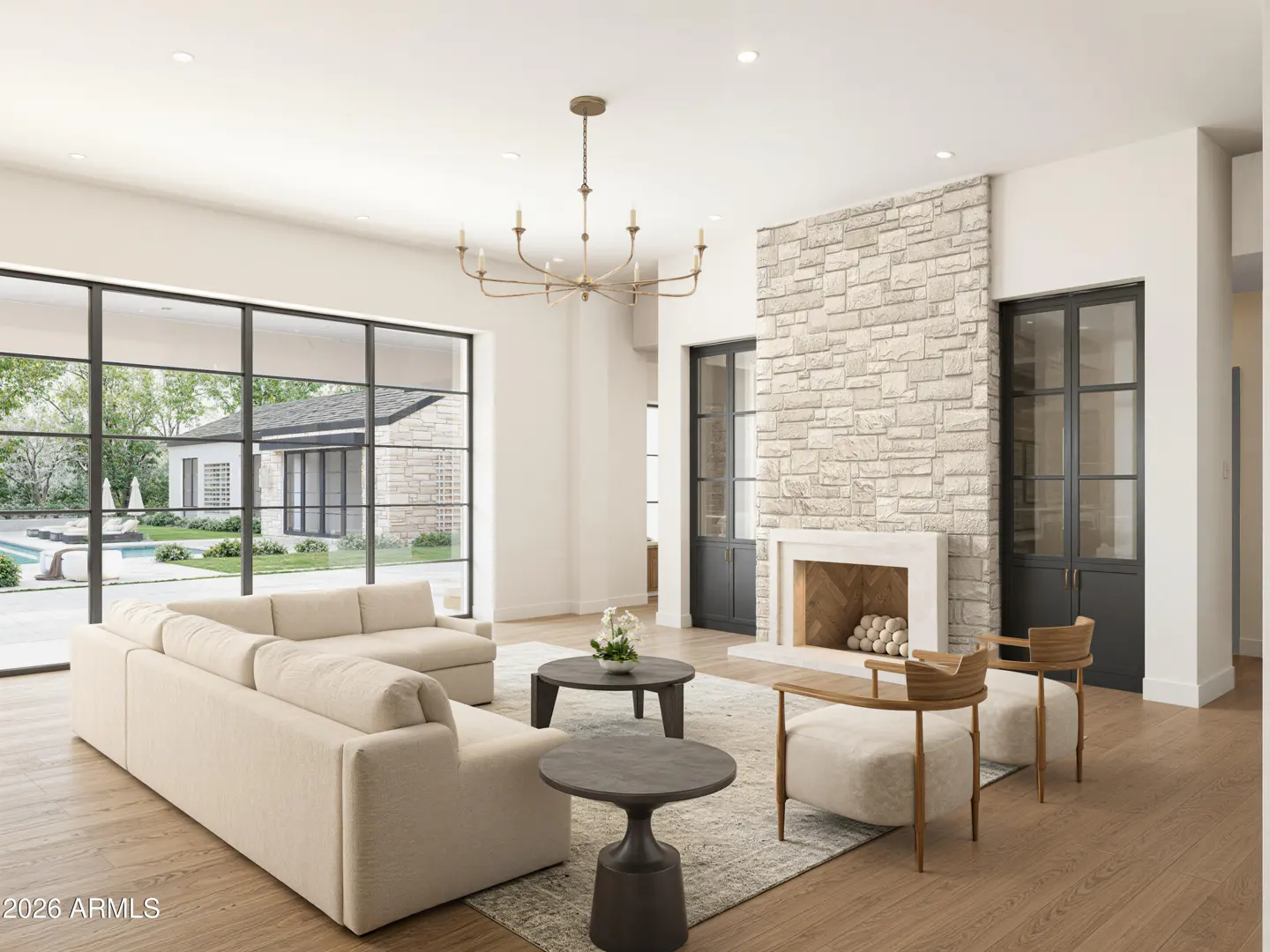 Bright living room with a stone fireplace, beige sofa, wood floors, and a view of the pool through large windows.