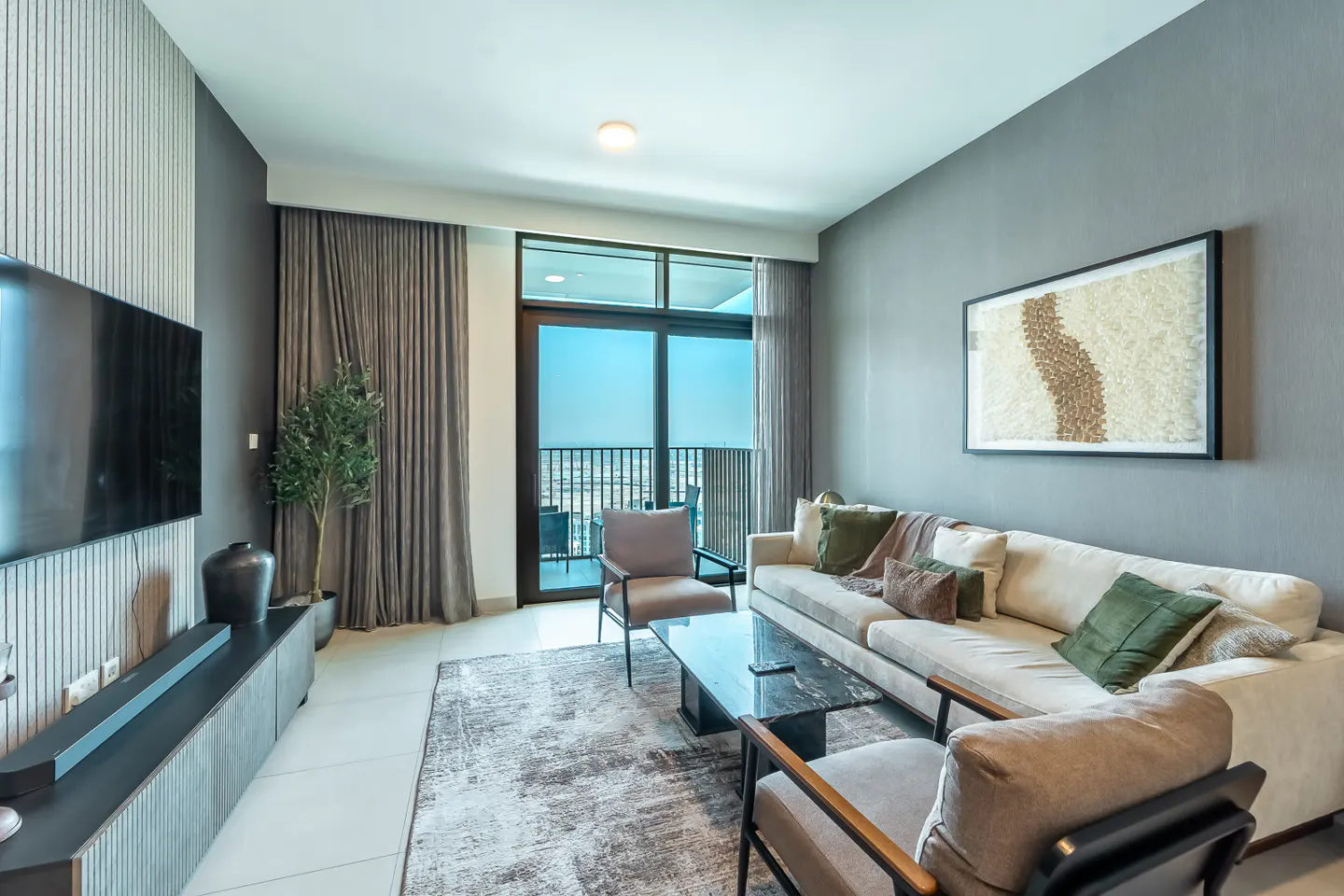 Living room with a beige sofa, two chairs, and a black marble coffee table on a gray rug. A TV and balcony are visible.