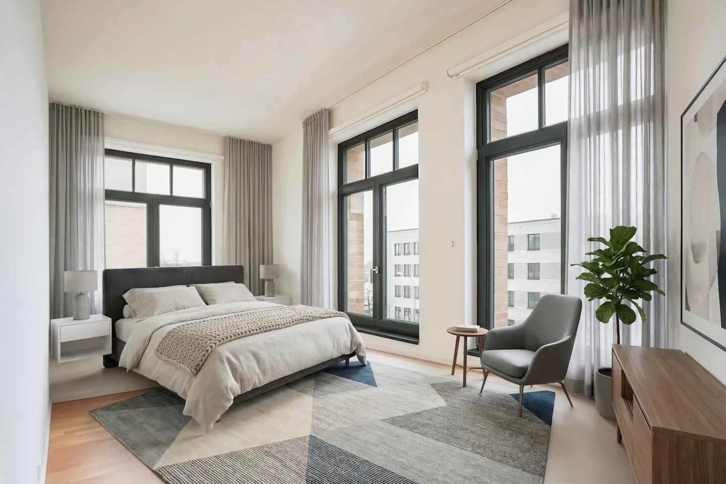 Bright bedroom with large windows, gray curtains, and a geometric rug. A bed, chair, and plant complete the modern design.