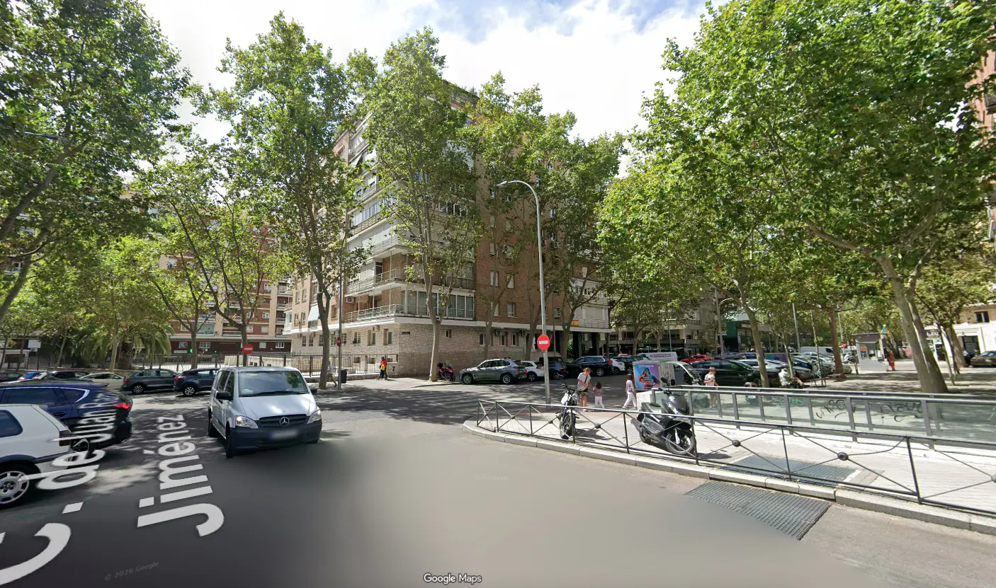 Street view of C. de Juan Jiménez in Madrid, Spain, with trees, buildings, cars, and pedestrians.