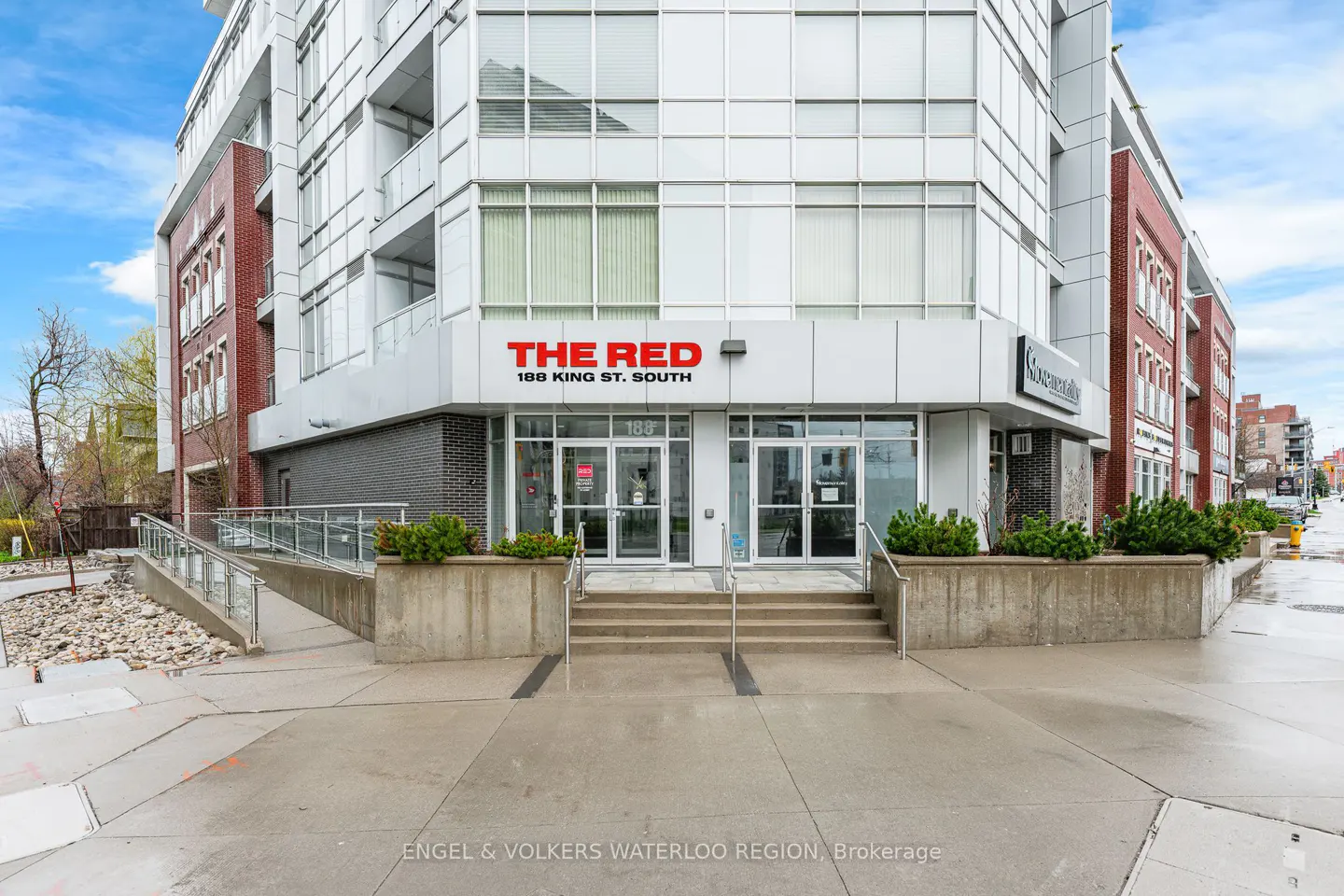 Exterior of "The Red" building at 188 King St. South. Modern architecture with white and red brick accents. Glass doors and windows.