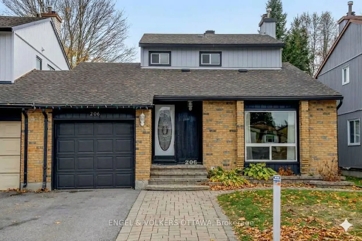 A tan brick house with a black garage door and front door, and a gray roof. A brick walkway leads to the front door.