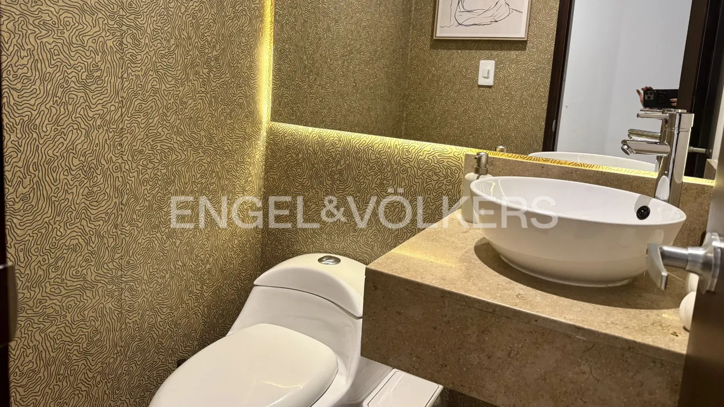 Modern powder room with gold topographic wallpaper, white vessel sink, stone vanity, and a large mirror with LED lighting.