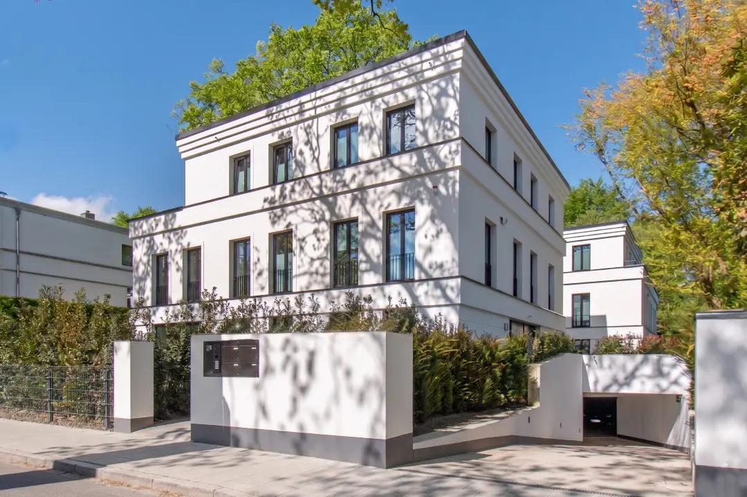 Exterior of a modern, three-story white building with black framed windows and a private underground garage.