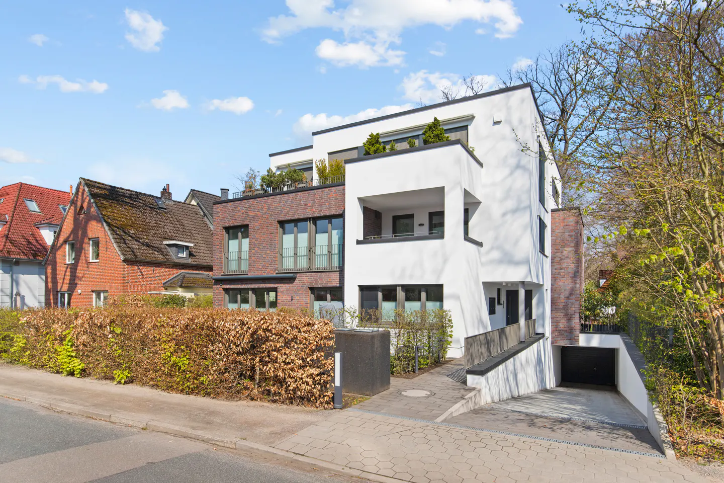 Modern house with white and brick facade, black framed windows, and a driveway leading to a garage.