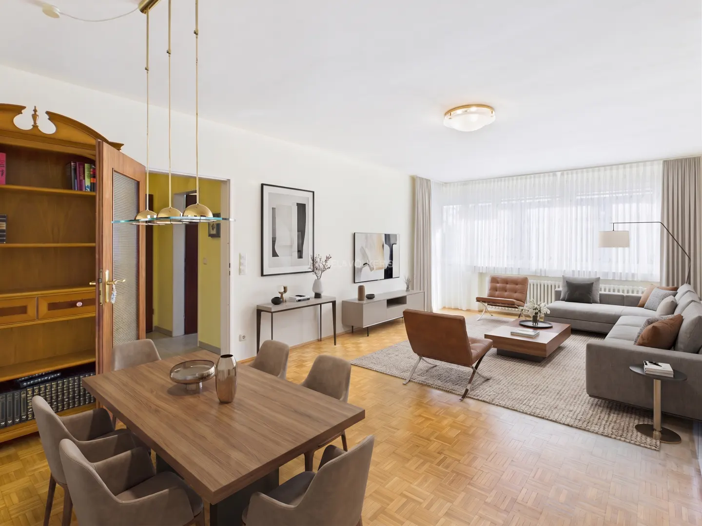 A bright, open-concept living and dining area with wood floors and modern furniture. A gray sectional sofa and dining table with six chairs are visible.