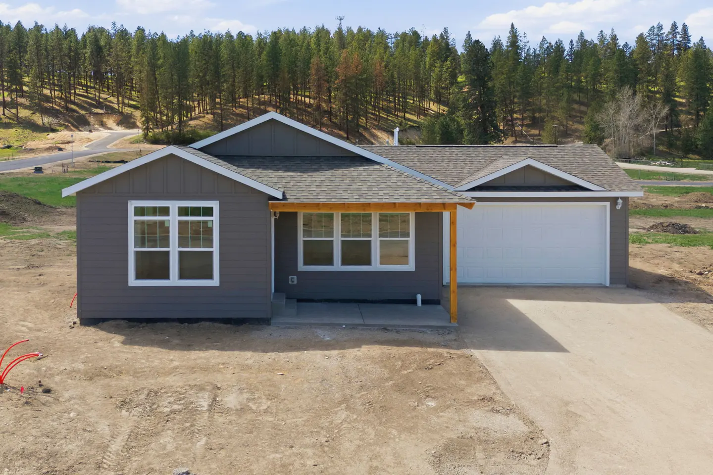 A gray single-story house with a white garage door and trim, and a wood porch.
