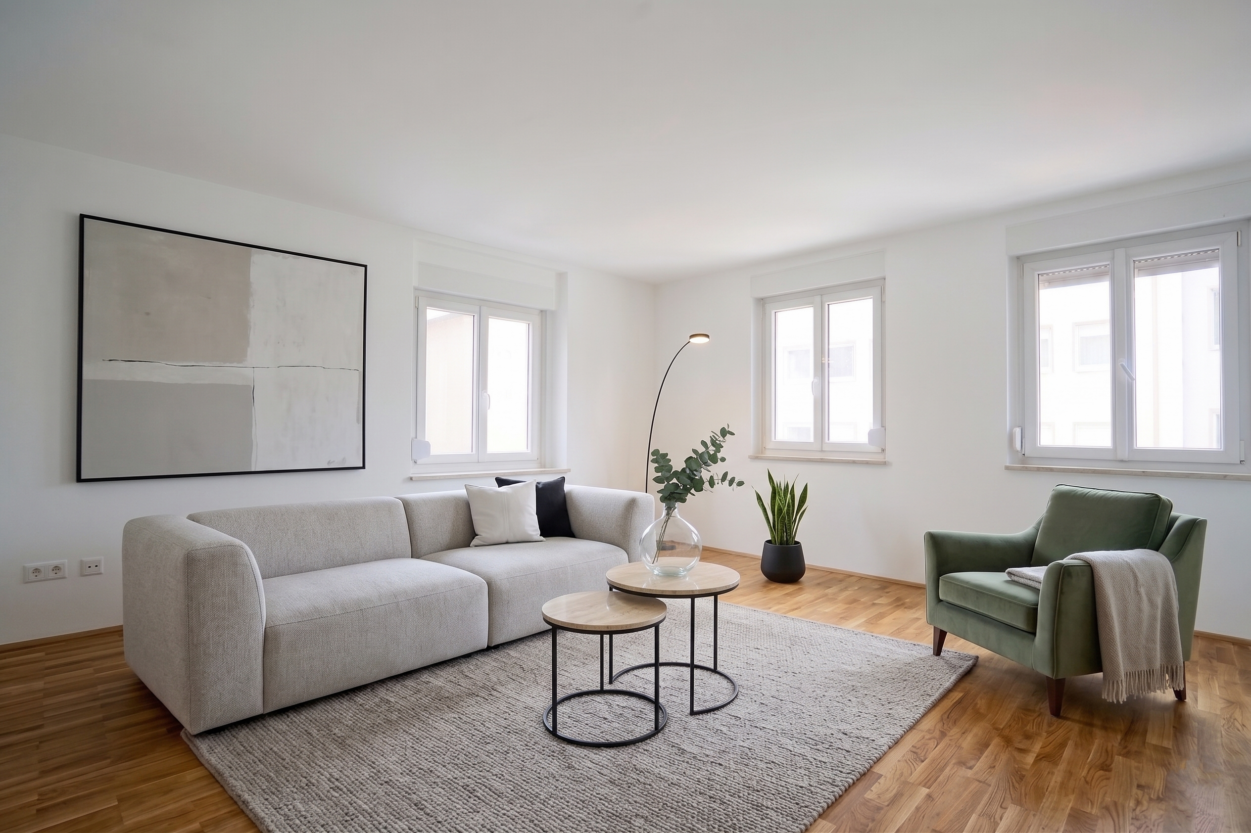 Bright living room with a light gray sofa, green armchair, two round coffee tables, and abstract art on a white wall. [AI-generated text] [AI-modified]