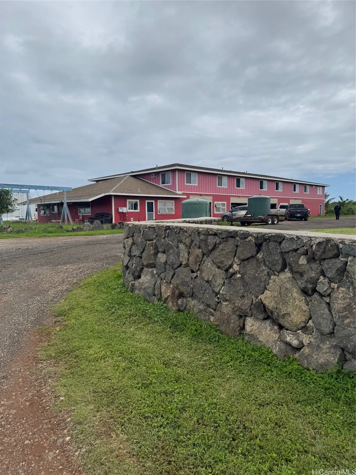Exterior view of a pink and red building with a stone wall in front on a cloudy day.