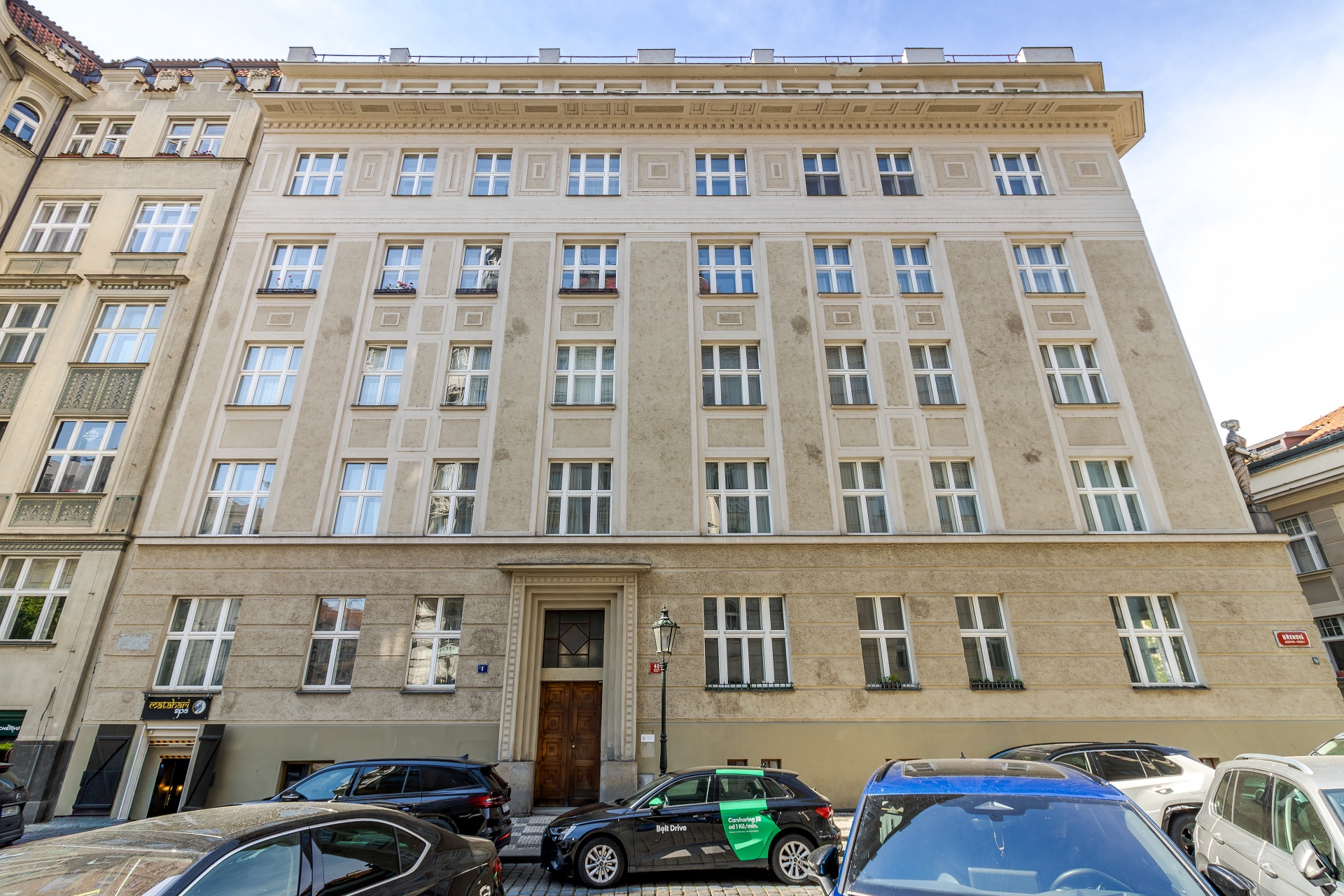 A beige, multi-story historic apartment building in Prague with symmetrical windows and a central wooden entrance door.