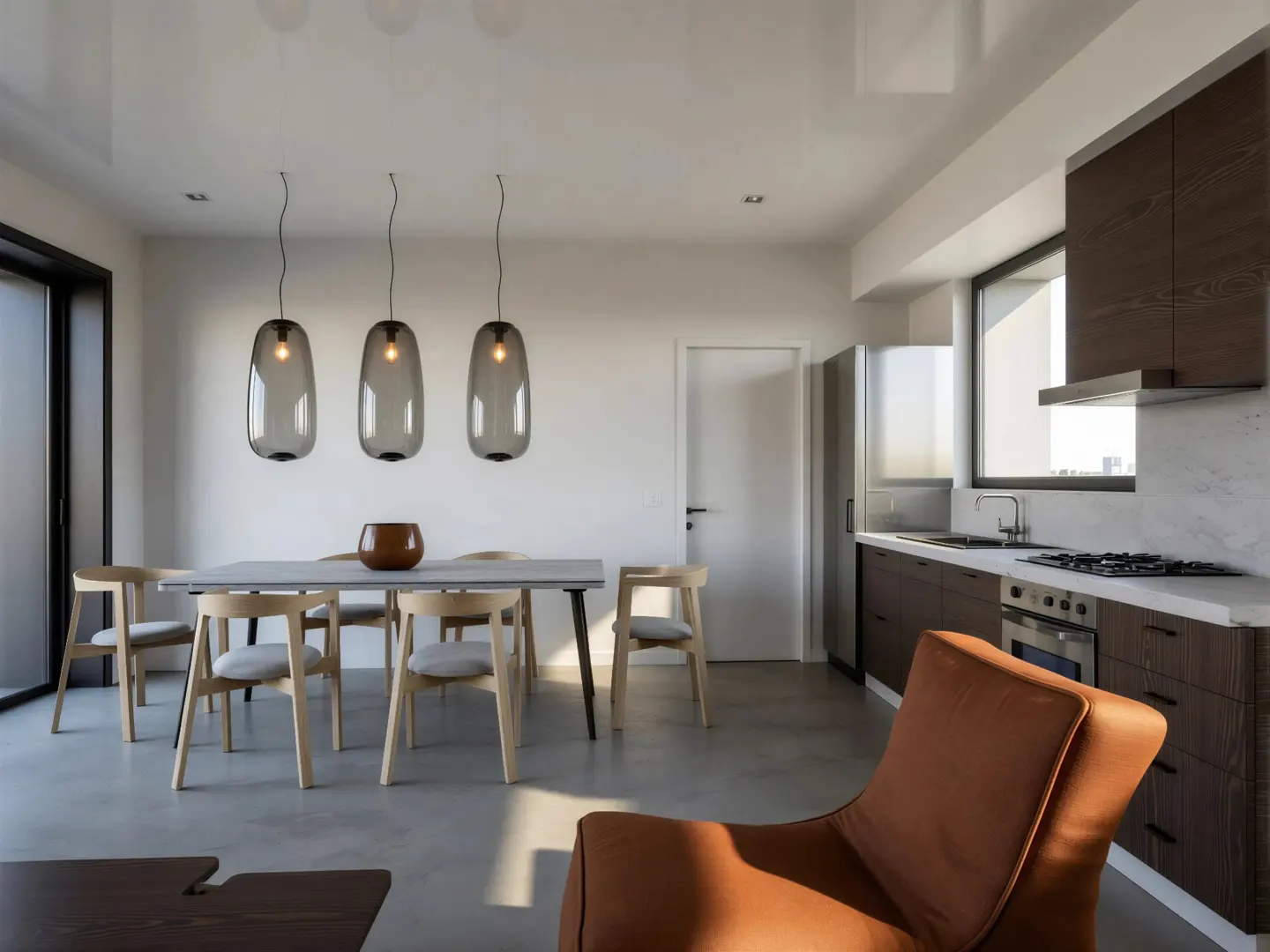 A modern, open-concept living space with a dining table, kitchen, and brown leather chair. Three gray pendant lights hang above the table.