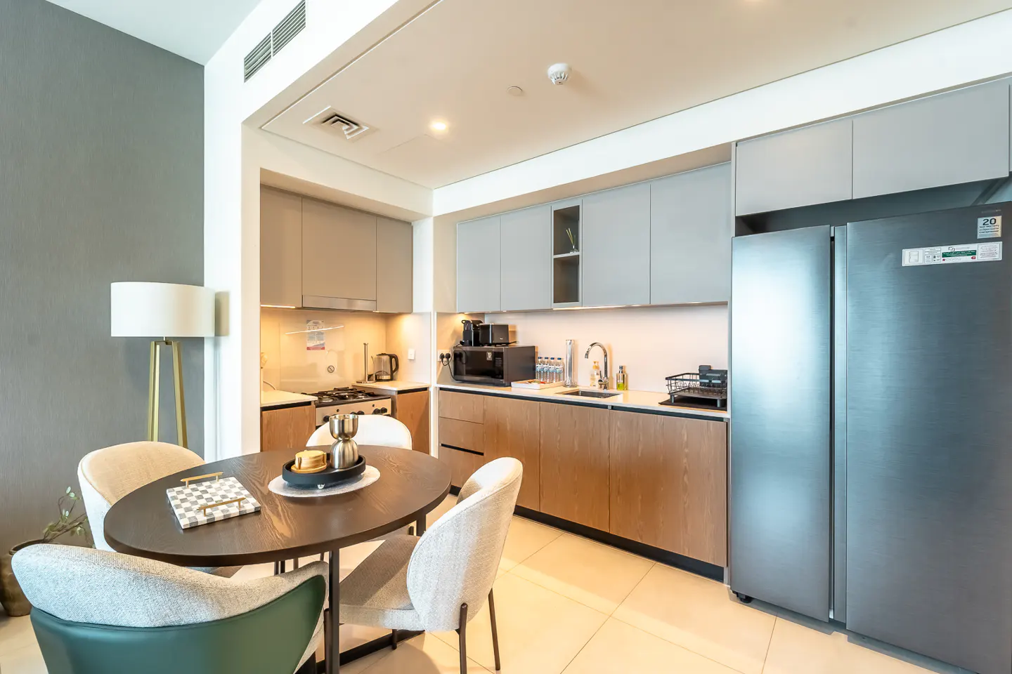 A modern kitchen with gray cabinets, stainless steel appliances, and a dark wood dining table with four chairs.
