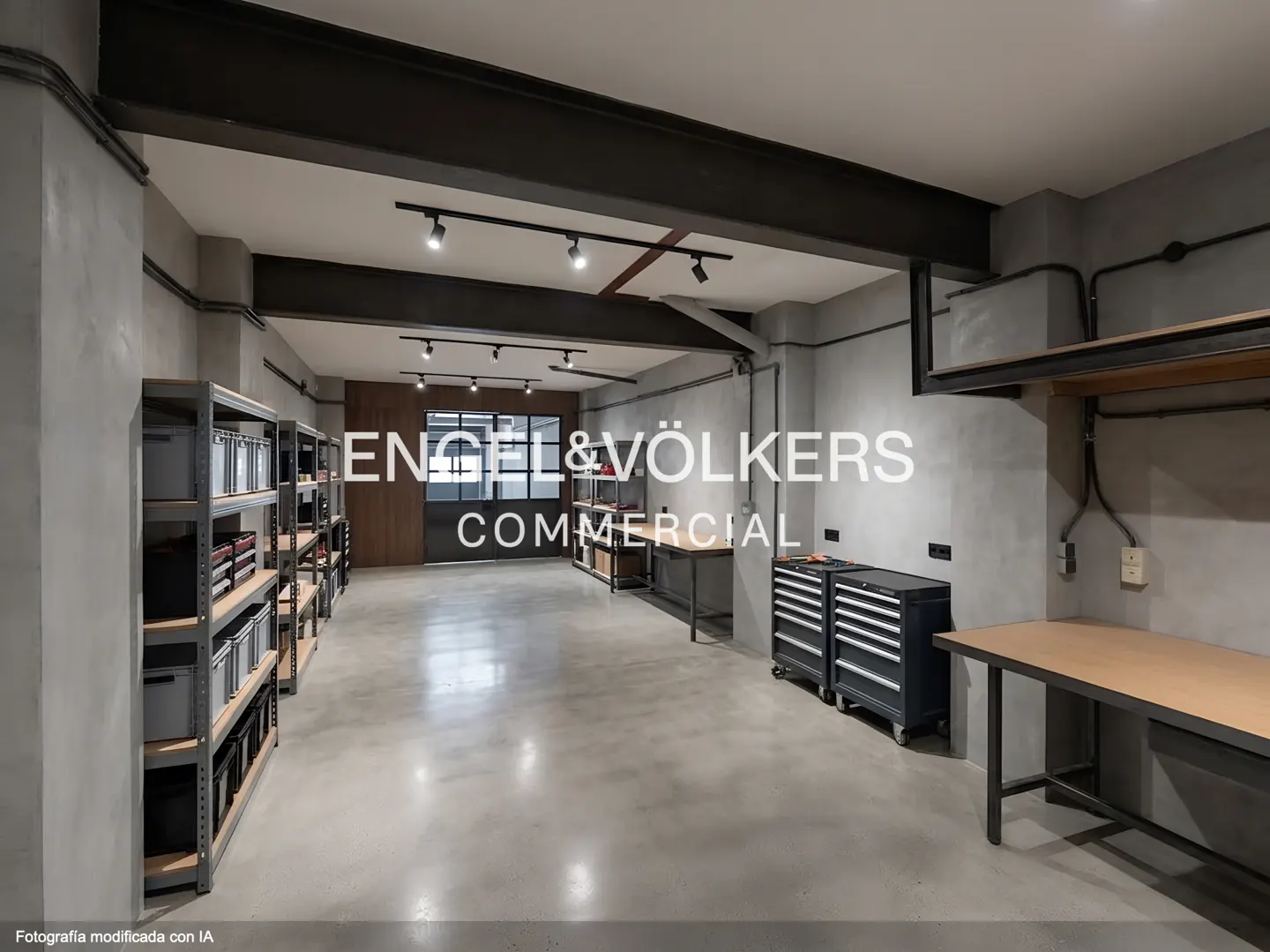 A commercial space with gray walls, metal beams, shelving, work tables, and tool chests. The Engel & Völkers logo is superimposed.