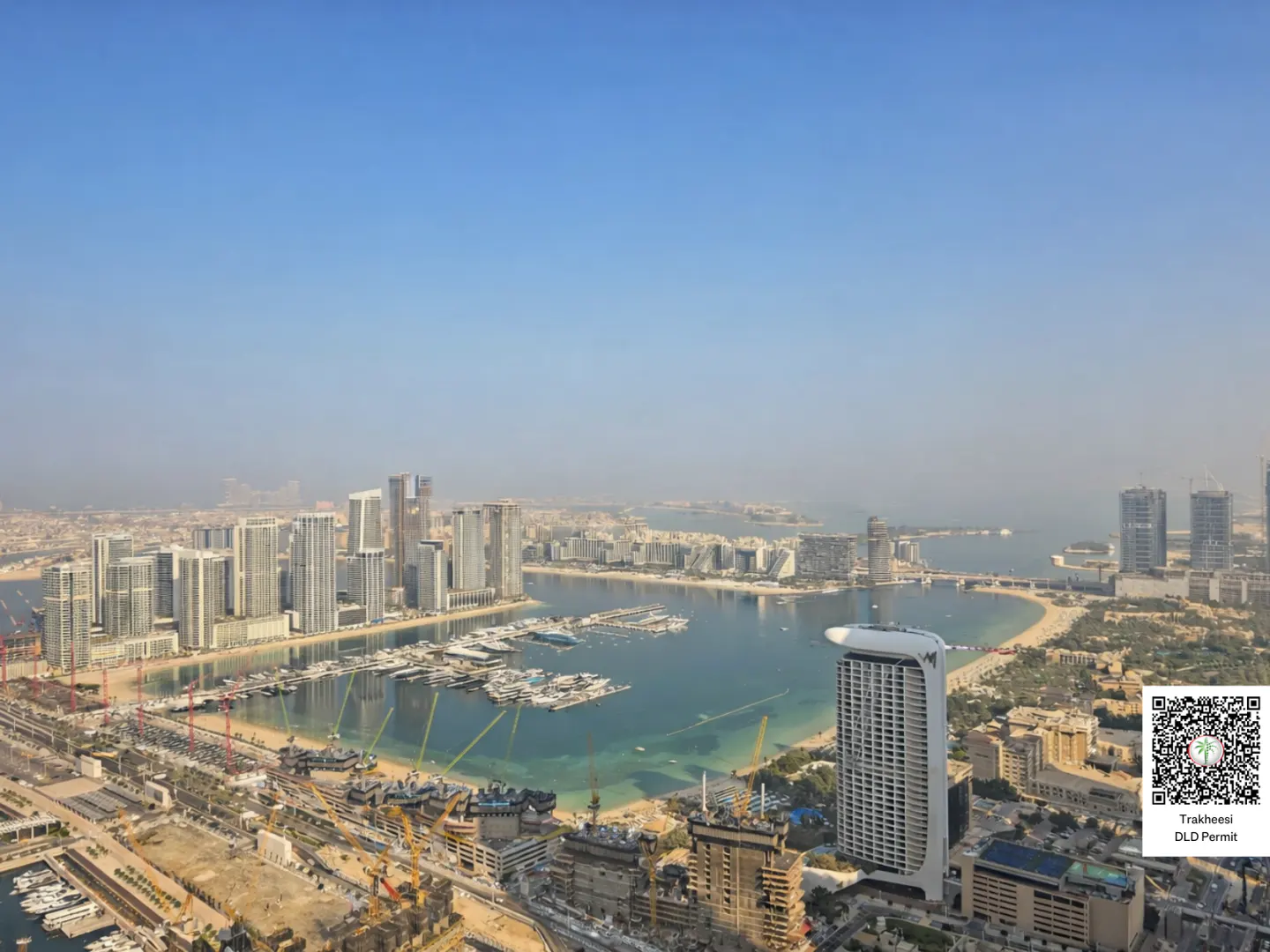 Aerial view of Dubai's skyline, showcasing modern buildings, a marina filled with yachts, and a clear blue sky.