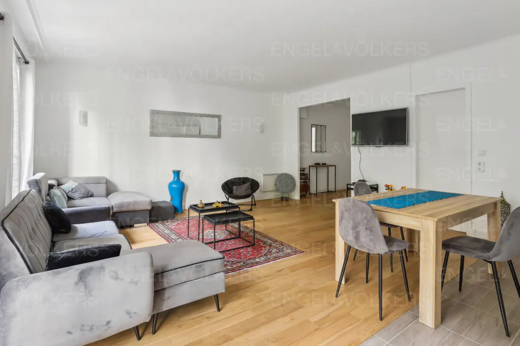 Living room with gray sectional sofa, wood floors, dining table with gray chairs, and a blue vase.