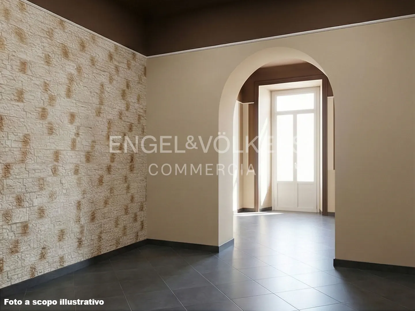 An empty room with beige walls, a dark brown ceiling, and gray tile floors. An arched doorway leads to a bright room with a white door.
