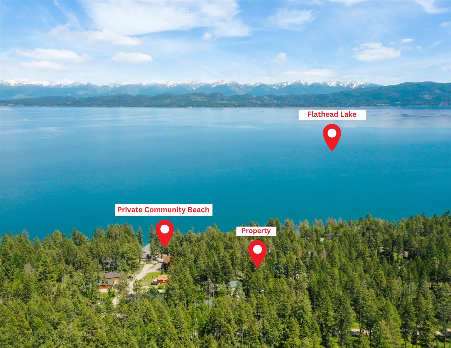 Aerial view of a property near Flathead Lake, Montana. Green trees surround the property and a private community beach. Snow-capped mountains are visible in the background.