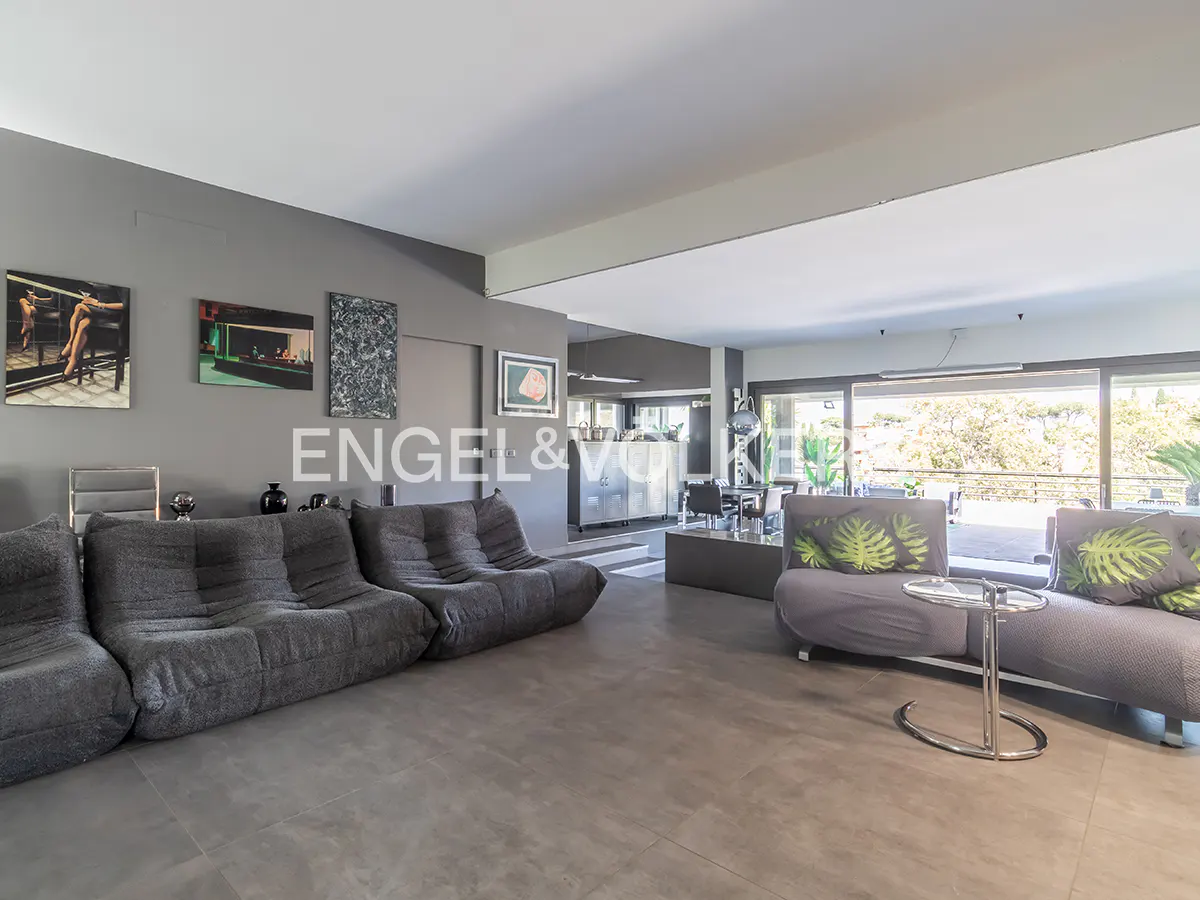 A modern living room with gray modular sofas, gray walls with art, and a view through sliding glass doors.