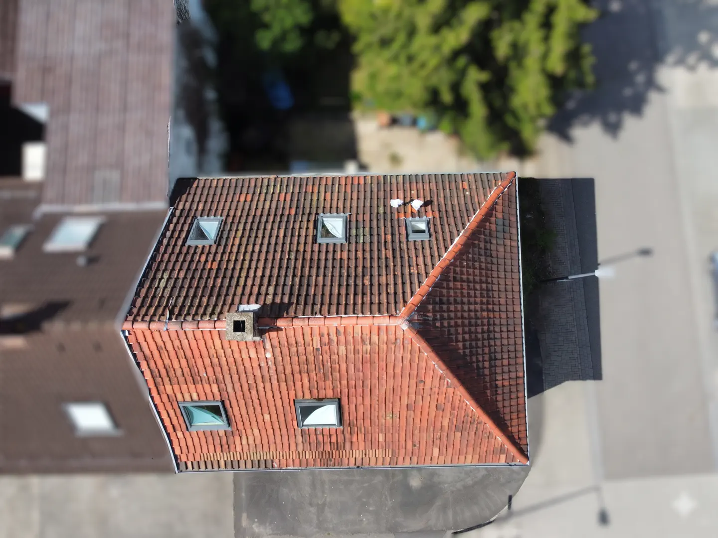 Aerial view of a building with a red tile roof, skylights, and a chimney.