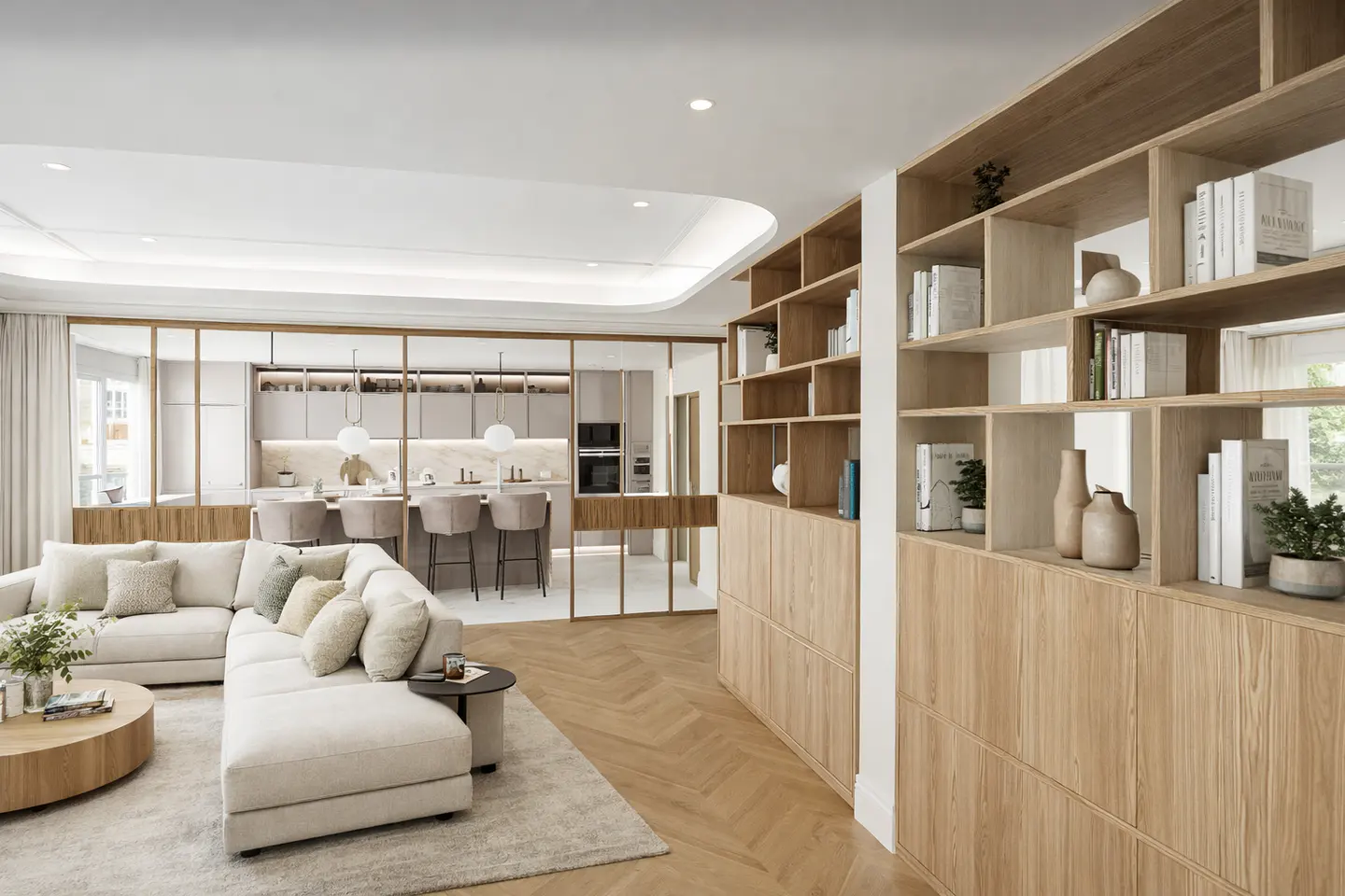 Bright, open-concept living space with a white sectional sofa, wood bookshelf, and kitchen with bar seating in the background.