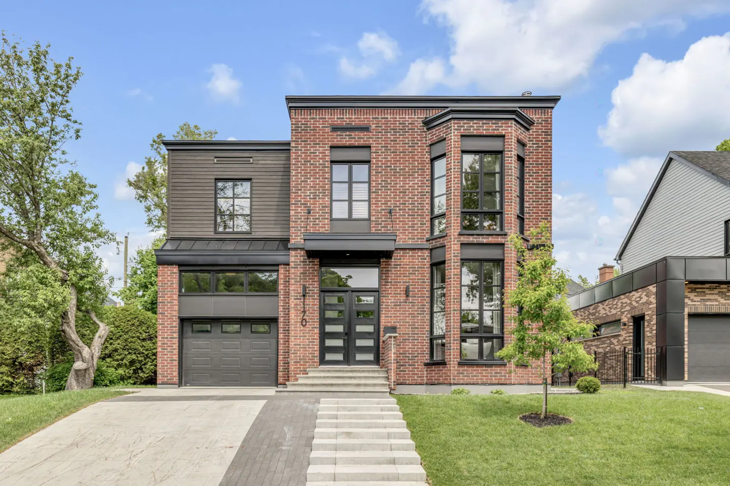 Modern two-story brick home with black trim, a single-car garage, and concrete steps leading to a double front door.