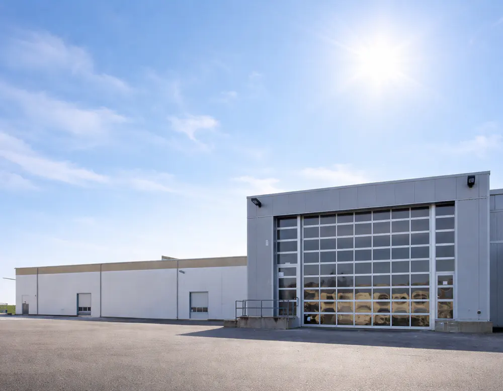A commercial building with a large garage door under a blue sky.