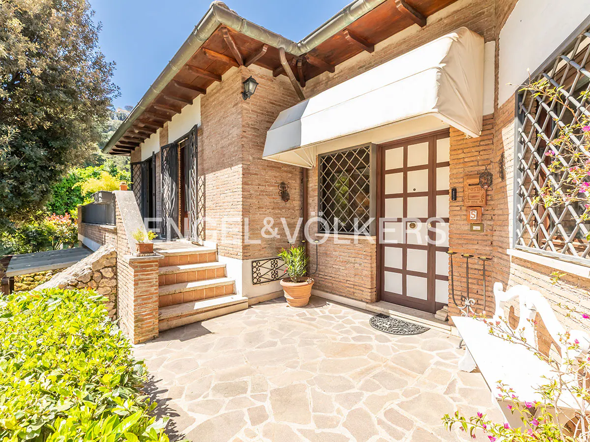 Exterior of a brick house with a white awning over the front door and a stone patio.
