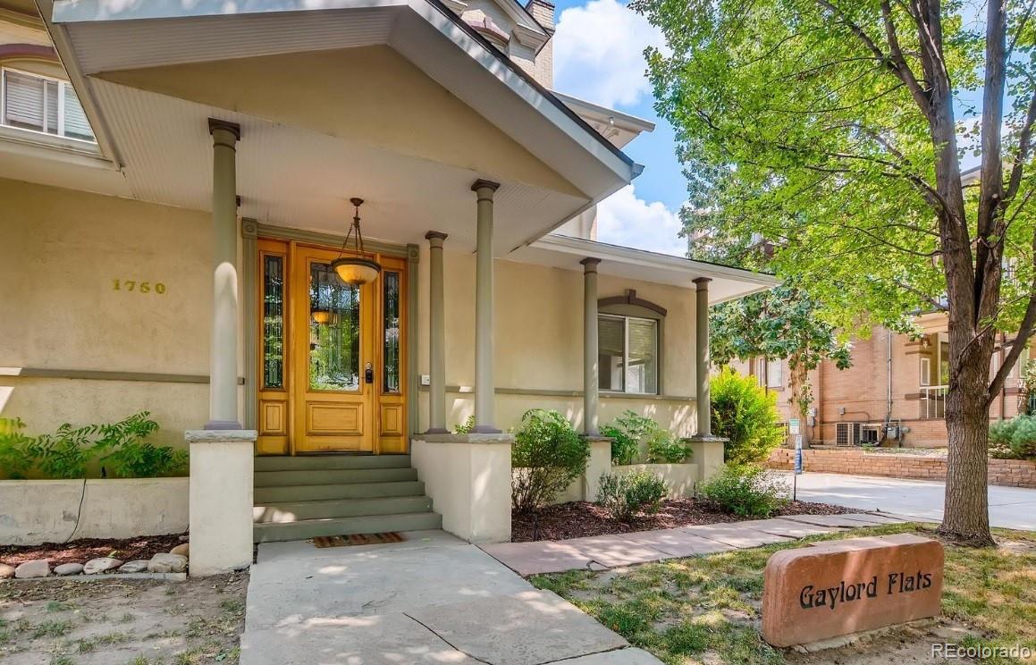 Exterior view of Gaylord Flats with a yellow door, columns, and a stone sign on the lawn.