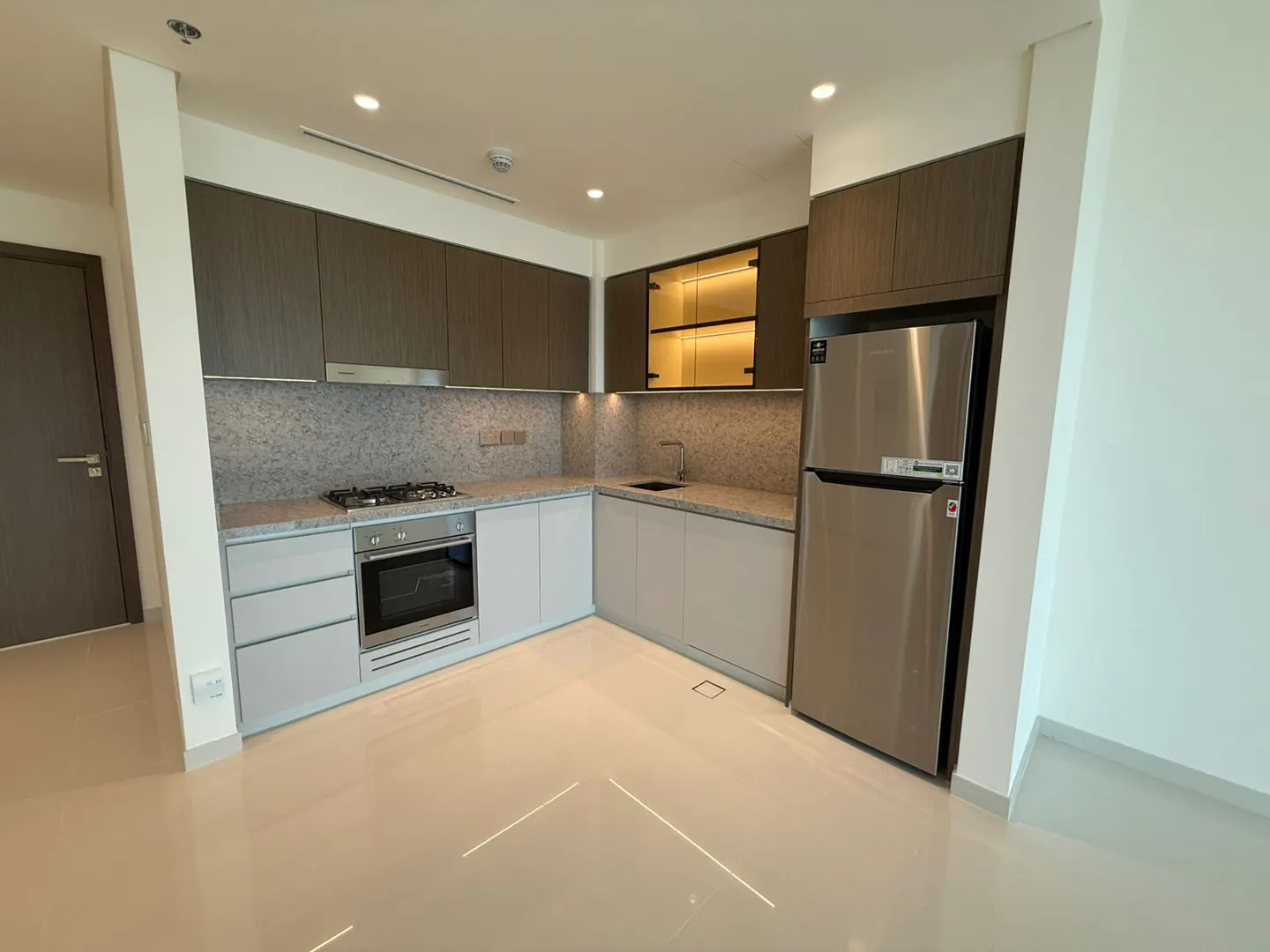 A modern kitchen with brown and white cabinets, stainless steel appliances, and light beige tile flooring.