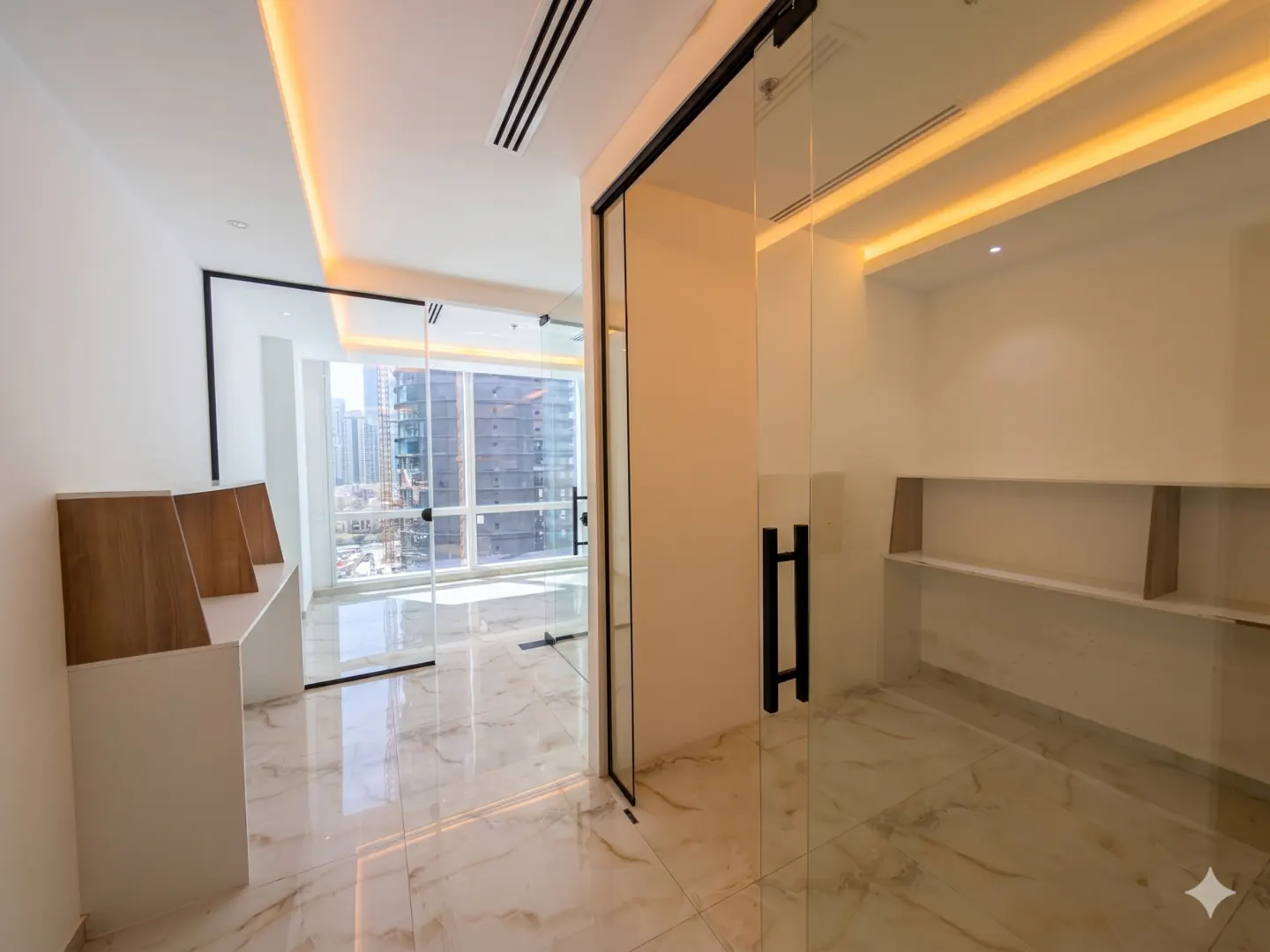 Modern office space with marble floors, glass doors, and city views. White walls and warm lighting create a bright, airy atmosphere.