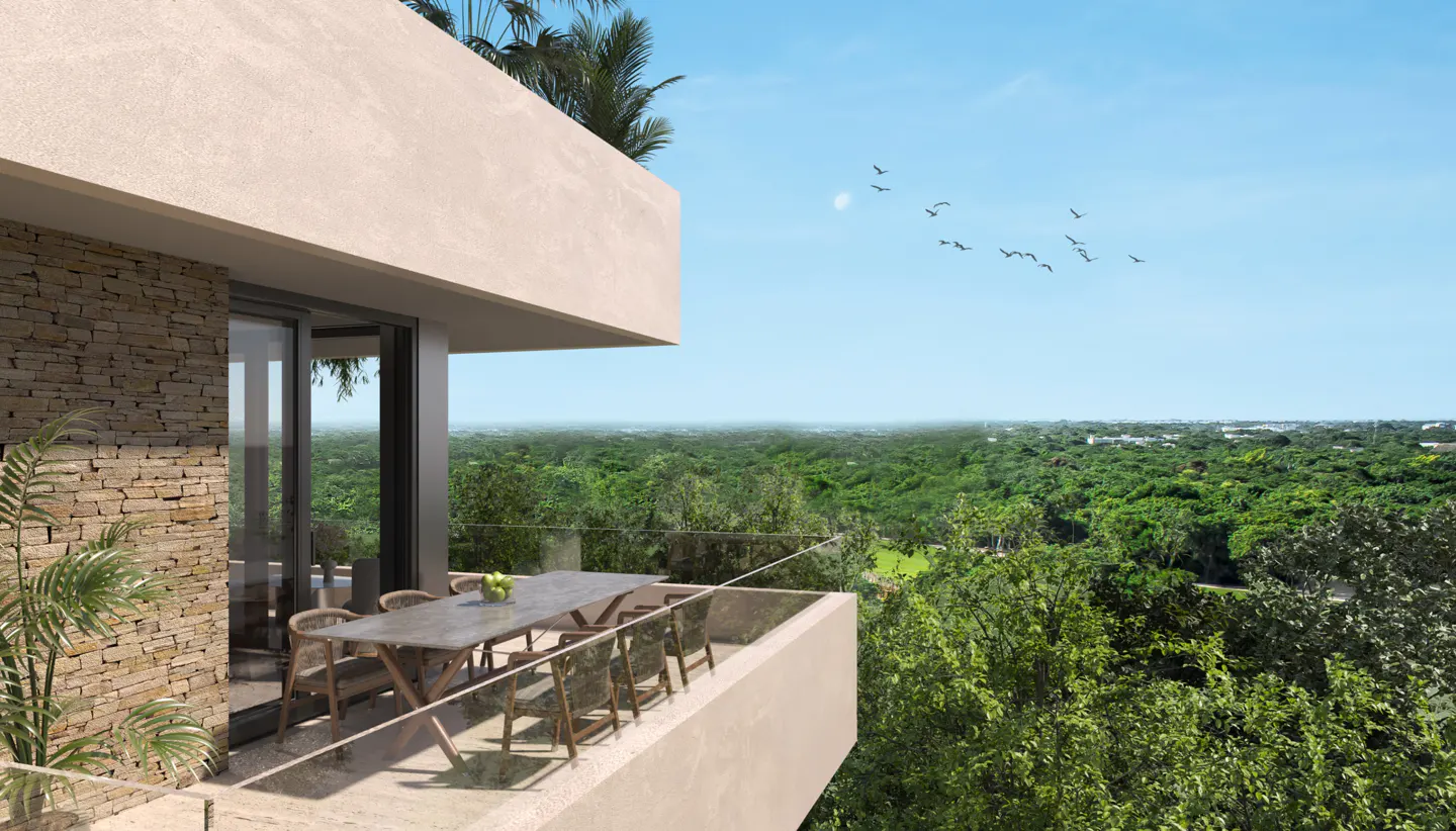 Balcony view of a modern home with a stone wall, table, chairs, and a lush green forest in the background under a blue sky with birds.