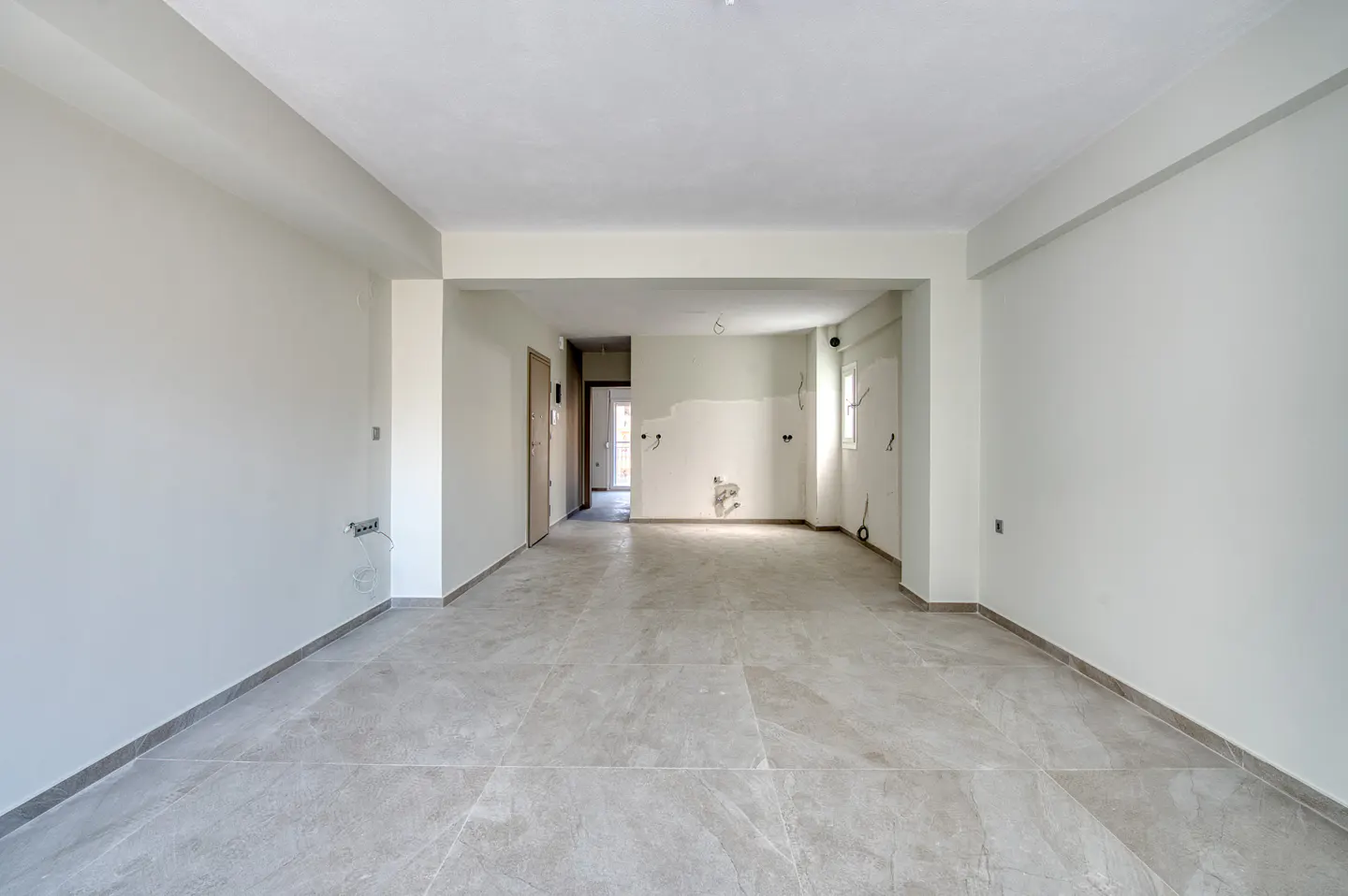 Empty room with gray tile floor, white walls, and open doorway to another room. Electrical wiring is visible.