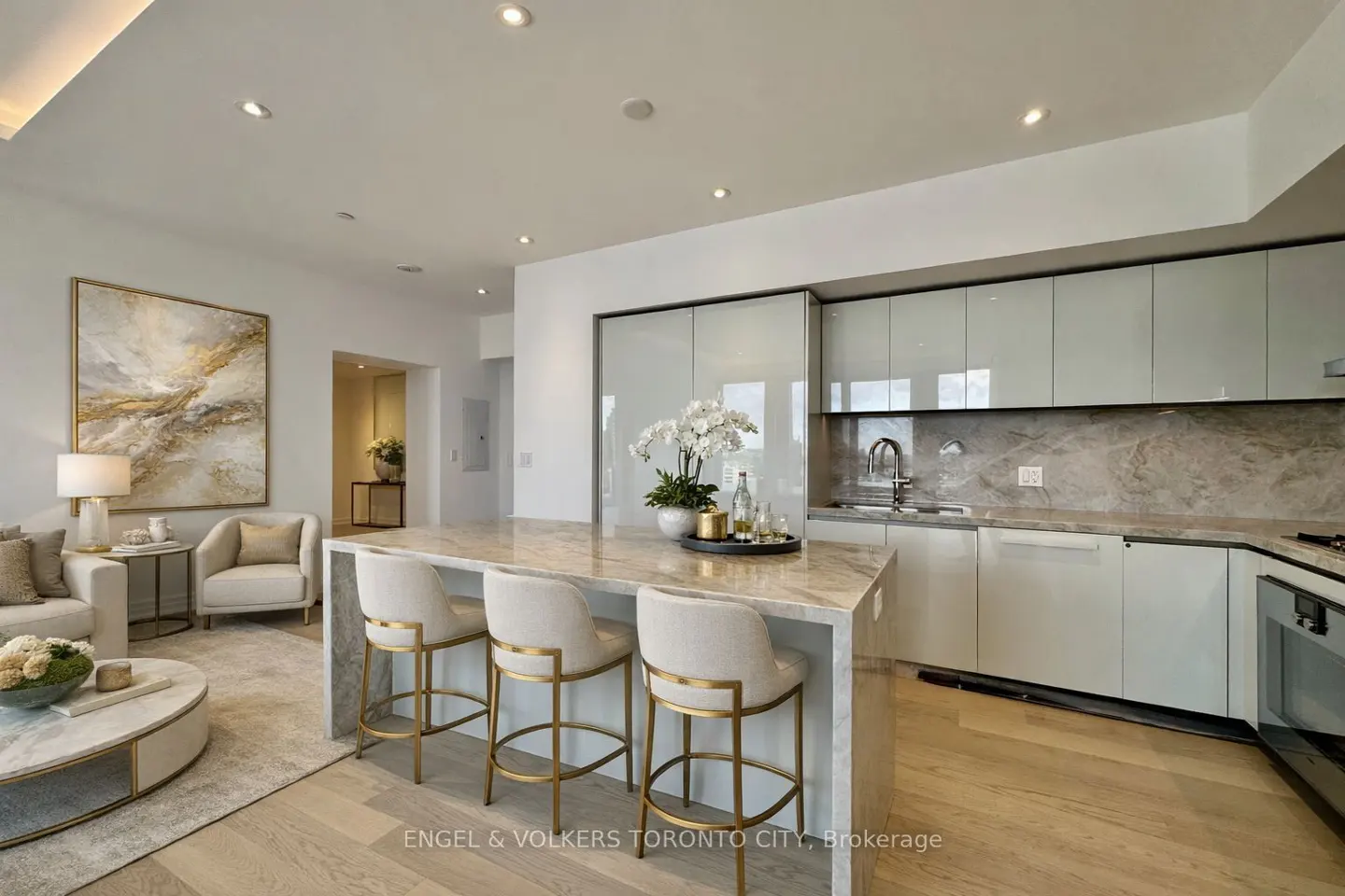A modern condo interior with a kitchen island, three bar stools, and a living area with a painting.