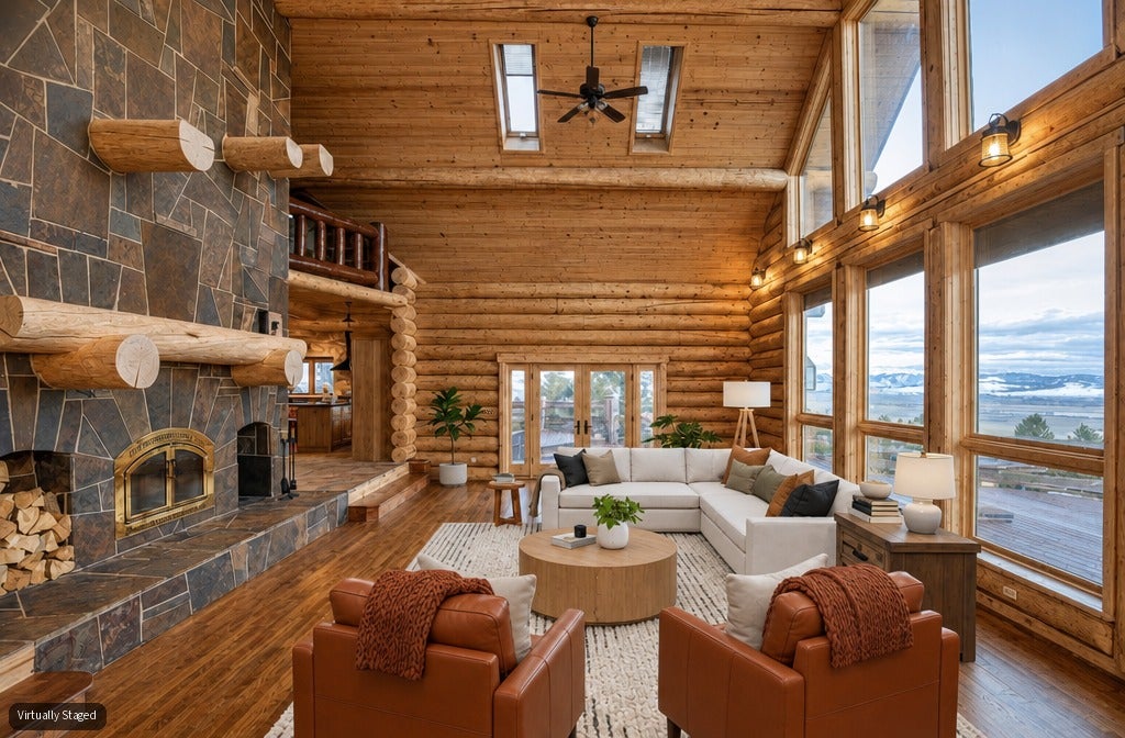 Rustic log cabin living room with stone fireplace, white sectional, two leather armchairs, and floor-to-ceiling windows. [AI-generated text]