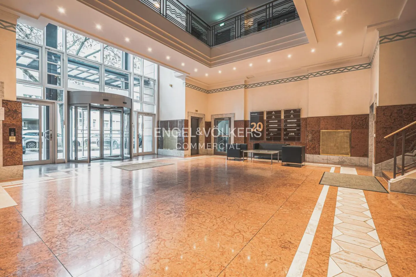 A spacious lobby with a revolving door, marble floors, and an Engel & Volkers Commercial sign.