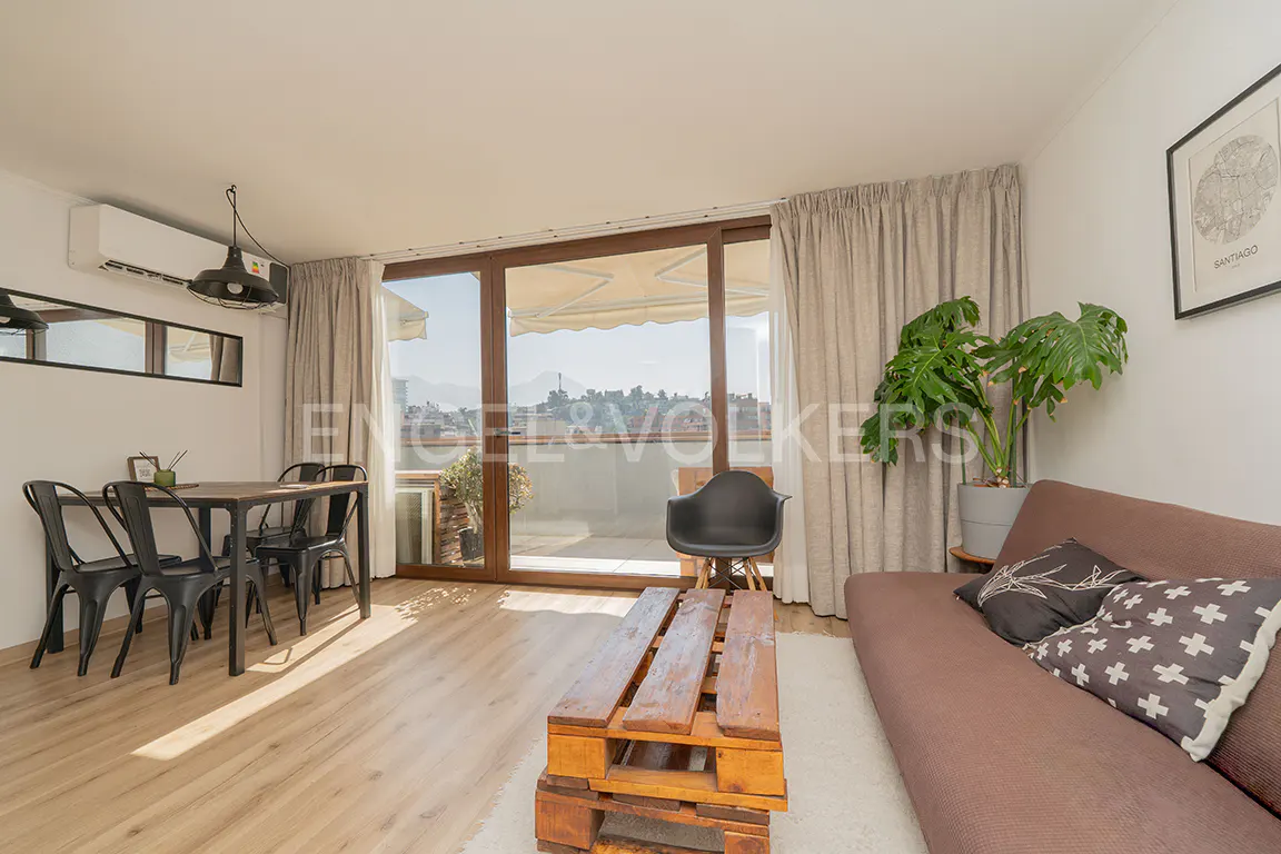 Bright living room with wood floors, brown sofa, pallet coffee table, dining set, and balcony with city view.